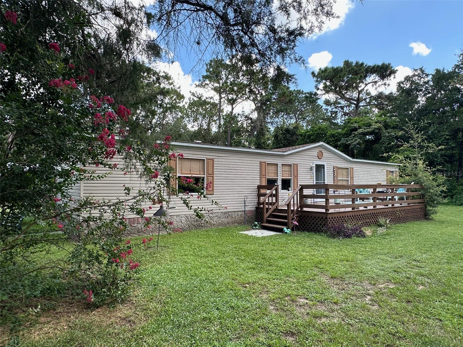 One or more photo(s) has been virtually staged. Dreaming of a tranquil country lifestyle? This fabulous mobile home is perfectly situated on nearly 2.5 acres of picturesque land, offering an ideal blend of space, privacy, and charm. Nestled in a friendly neighborhood, this well-maintained double-wide features a spacious and inviting layout with a desirable split floor plan. Step outside to discover front and rear decks that beckon you to relax and soak in the fresh air and stunning views. The rear addition boasts a cozy enclosed porch and a convenient storage room, which could easily serve as an office if you add a window A/C unit. The master bedroom is a true sanctuary, complete with a walk-in closet, luxurious garden tub, dual sinks, and a separate shower. The heart of the home is the welcoming kitchen, offering ample cabinets and counter space while overlooking the expansive park-like backyard. The living room features a warm and inviting wood-burning fireplace, perfect for cozy evenings spent indoors.Outside, you’ll find a versatile barn with four stalls, along with a covered pole barn and carport area, ideal for your hobbies or animals. The backyard is a true oasis, complete with a designated burn area and endless opportunities for outdoor adventures. Fully fenced and gated, this property provides both security and peace of mind. Plus, with horse trails just at the end of the street, you’ll enjoy easy access to nature and exploration. Recent updates include a new roof in 2011 and A/C in 2015, ensuring comfort and reliability. Don’t miss your chance to embrace country living at its finest! Hurry, homes like these don't last long!