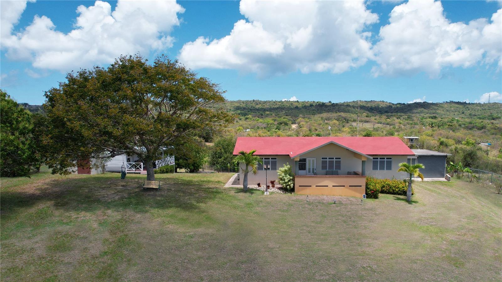 From its grand entrance in the bucolic neighborhood of Puerto Real to its vaulted interiors, this family owned residence has a stately appearance. Â The elegant home is set back on a hilltop and surrounded by cool trade winds, majestic views of the Caribbean, and tranquil rolling hills and meadows. Â The property has 1.6 acres of privacy, the land is scattered with a myriad of fruit trees, including breadfruit, mango, pigeon peas, soursop, gooseberry, lemon, and a variety of plantains and bananas.
Built to withstand, the sturdy structure of poured concrete is comfortably designed, appointed, and spacious. Â The property features an open and generously sized living room and dining room with granite countertops, three bedrooms, two bathrooms and a separate two bed, one bath guest bungalow. Â Well fenced and fully equipped with a security system, air conditioning, solar system, generator, a dual chamber cistern that holds a rain water and public water supply, and a separate two car garage. The large garage has high ceilings and can hold a second story and be easily converted into an additional unit.
Easily accessible from the airport and at just five minutes from Esperanza, Playa Negra and the Playa Grande reserve, this home has all the comforts one could ask for.
Previously sold with 2 adjacent lots that have now been sold, price changes reflect the selling off of the 2 adjacent lots.
