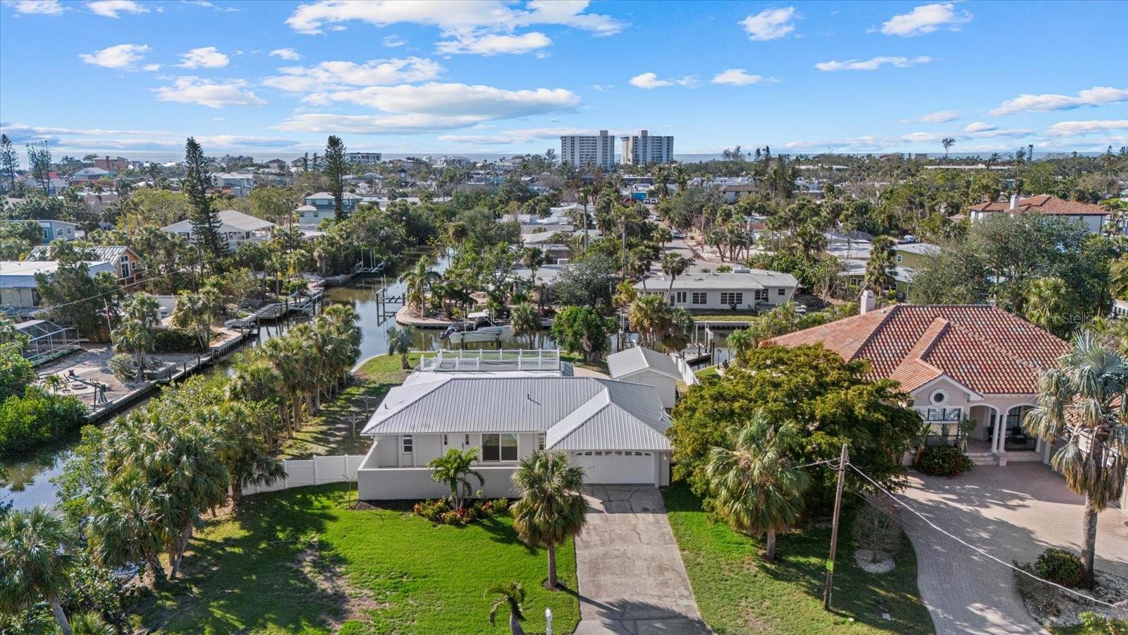 ***SELLER FINANCING AVAILABLE*** Tucked away on a quiet dead-end street, this exceptional waterfront estate on Siesta Key offers the perfect balance of seclusion and accessibility. Situated on an oversized 0.40-acre corner lot with 260 feet of water frontage and coveted western exposure, the property provides direct access to the Intracoastal Waterway—ideal for boating enthusiasts and water lovers. Just one mile from Siesta Key Village and the beach, the location allows for effortless enjoyment of island life while offering a private retreat. Move-in ready and untouched by flood damage, the estate includes two separate structures: a 2,000-square-foot main residence featuring an updated kitchen, and a versatile 280-square-foot detached building with a full bath—perfect for a guest suite, office, or creative studio. A newer metal roof and hurricane-impact windows and doors ensure lasting protection and peace of mind. Designed for outdoor living, the home features a spacious pool area with a large paver lanai, ideal for entertaining or relaxing. The property also includes a brand-new 10,000 lb boat lift, a double jet ski lift, and a newly installed well for efficient irrigation. After a day on the water or at the beach, unwind on the rooftop terrace and enjoy stunning sunset views over the water. This is a great opportunity to own a thoughtfully enhanced property in one of Siesta Key’s most desirable locations—offering the best of coastal living with modern amenities, luxury features, and sustainable upgrades.