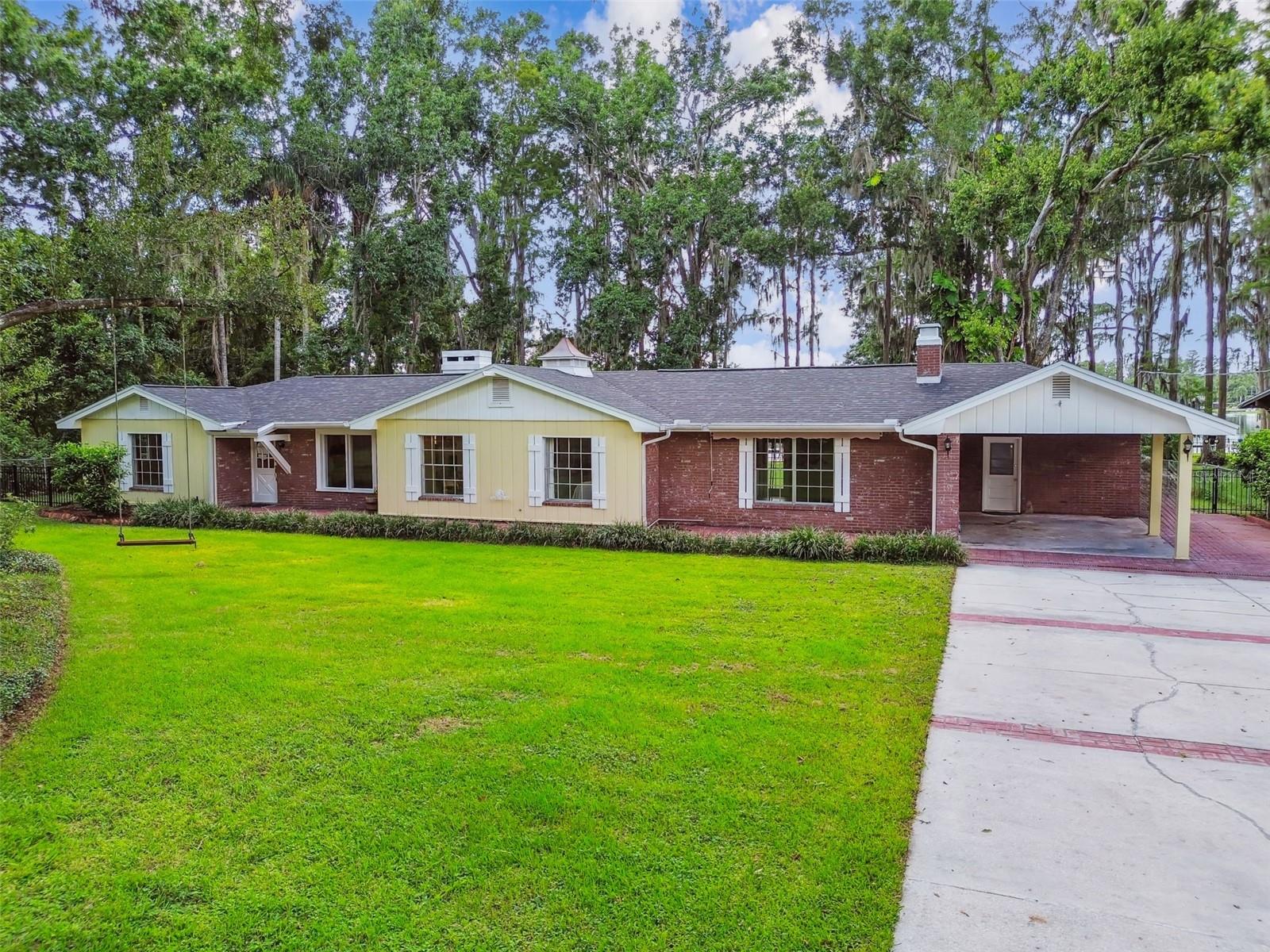 ONE OF A KIND LAKEFRONT HOME! Welcome to this charming and picturesque one-story ranch-style home, perfectly situated on 1.12 ACRES of serene lakefront property. This stunning residence boasts 3 bedrooms, 2 bathrooms, and an expansive BONUS ROOM, offering over 2,400 square feet of luxurious living space. PRIME LOCATION with NO HOA! Enjoy the FREEDOM and CONVENIENCE of a prime location without the constraints of an HOA. As you pass through the gate, you'll be captivated by the long driveway, towering trees, and lovely brick façade that complement the spacious front yard. Step inside to discover the great room, featuring a soaring EXPOSED BEAM CEIING and a stunning WOOD-BURNING FIREPLACE, perfectly centered between double French doors that lead out to the screened lanai with BREATHTAKING LAKE VIEWS. The entire home is adorned with elegant WOOD-LOOK TILE flooring. The dining room, with its large window showcasing front yard views, offers ample space for gatherings of all sizes. The gourmet kitchen is a chef's dream, featuring quartz countertops, under-cabinet lighting, a pull-out pantry cabinet, stainless steel appliances, and abundant storage. The kitchen seamlessly opens to the breakfast nook, where a bright bay window overlooks the expansive backyard. The generous primary suite offers premium views of Lake Holly and a private entrance to the patio. The adjoining bathroom features a soaking tub, separate shower, dual sinks, and a large linen closet just outside. The huge bonus room is incredibly versatile, perfect for a playroom, man cave, hobby room, or any other space you desire. The air-conditioned laundry room, conveniently located just outside the bonus room, provides ample space for both laundry and storage. The FULLY FENCED backyard, with 102 FEET of LAKE HOLLY FRONTAGE, is a magical retreat for enjoying with family, friends, and pets. Take a boat or kayak out on the lake, fish from the dock, or simply savor a cup of coffee while taking in the tranquil morning views or dazzling sunsets. Additional storage is available in the two storage sheds. This home is zoned for TOP SCHOOLS such as A-rated McKitrick Elementary, Martinez Middle, and Steinbrenner High Schools. Plus, enjoy peace of mind with a BRAND-NEW ROOF installed in 2025. Several new windows throughout the home! Don't miss the opportunity to make this extraordinary lakefront home your own. Schedule your showing today and prepare to fall in love!