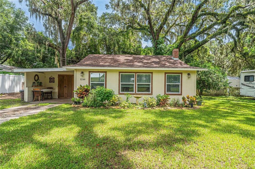 Take a step back in time in this fully restored 1953 Cottage within street view of Lake Weir.  It sits on .26 acres and has a 30 amp RV hook-up.  This beautiful home has an open floor plan with vaulted ceilings.  The new kitchen has corian countertops, a gas range, open concept shelving, real wood floors and ample space for a table.  The back porch has been converted into a laundry, pantry/prep room and is absolutely adorable.   The front porch is set up as a cozy extra living / office area.  Just out back by the estimated 500+ year old Oak tree there is a 12 x 16 air conditioned she shed or man cave.   The garage has been converted into a workshop and outdoor sitting area. The fenced backyard will keep your pets in and give you privacy.  It has 3 orange and 1 grapefruit tree.   This one is priced right and ready to sell.  Roof is new in 2023, Electrical updated in 2010.