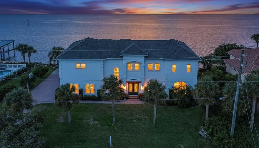 Experience the pinnacle of luxury living in this magnificent waterfront estate on Ormond Beach's most esteemed street, John Anderson just a couple blocks from the beach, where elegance meets comfort at every turn. Boasting panoramic views of the Intracoastal and Tomoka Basin, this extraordinary riverfront residence is a haven for those who cherish fishing, sunset vistas, and local wildlife. Impeccably renovated, the home features four spacious bedrooms and four and a half baths, each offering sweeping water views and refined style. Upon entering, you're met with an inviting ambiance accented by stunning new marble floors throughout the main living areas. The gourmet kitchen is a culinary delight, featuring granite countertops, an oversized breakfast bar, and generous space for hosting friends and family. Enjoy privacy for guests in a dedicated suite tucked away in the south wing, while upstairs offers three additional bedrooms, a grand family room, and a flexible space ready to suit you unique vision. Retreat to the owner's suite, complete with a spa-inspired walk-in shower, dual vanities, and a private balcony overlooking tranquil waters. Outdoors, unwind in your solar-heated saltwater pool and spa, protected by automatic retractable screens and surrounded by elegant travertine decking. Established in 2022, the custom dock offers two boat houses and a jet ski lift for effortless river access, complemented by a newly built coquina seawall added in 2024. This smart home embraces modern technology, featuring advanced security systems with cameras and remote control, motorized window shades, automated awnings, Lutron lighting, and Hayward Omnilogic pool and spa management. The pristine garage, equipped with Martin epoxy floors and an electric bike lift, demonstrates meticulous attention to detail. Energy-saving open-cell foam insulation in the attic boosts efficiency, while lush, mature landscaping truly sets this property apart. Every inch of this home radiates pride of ownership, schedule your private tour today and discover a waterfront masterpiece in one of Ormond Beach's most coveted beachside areas.