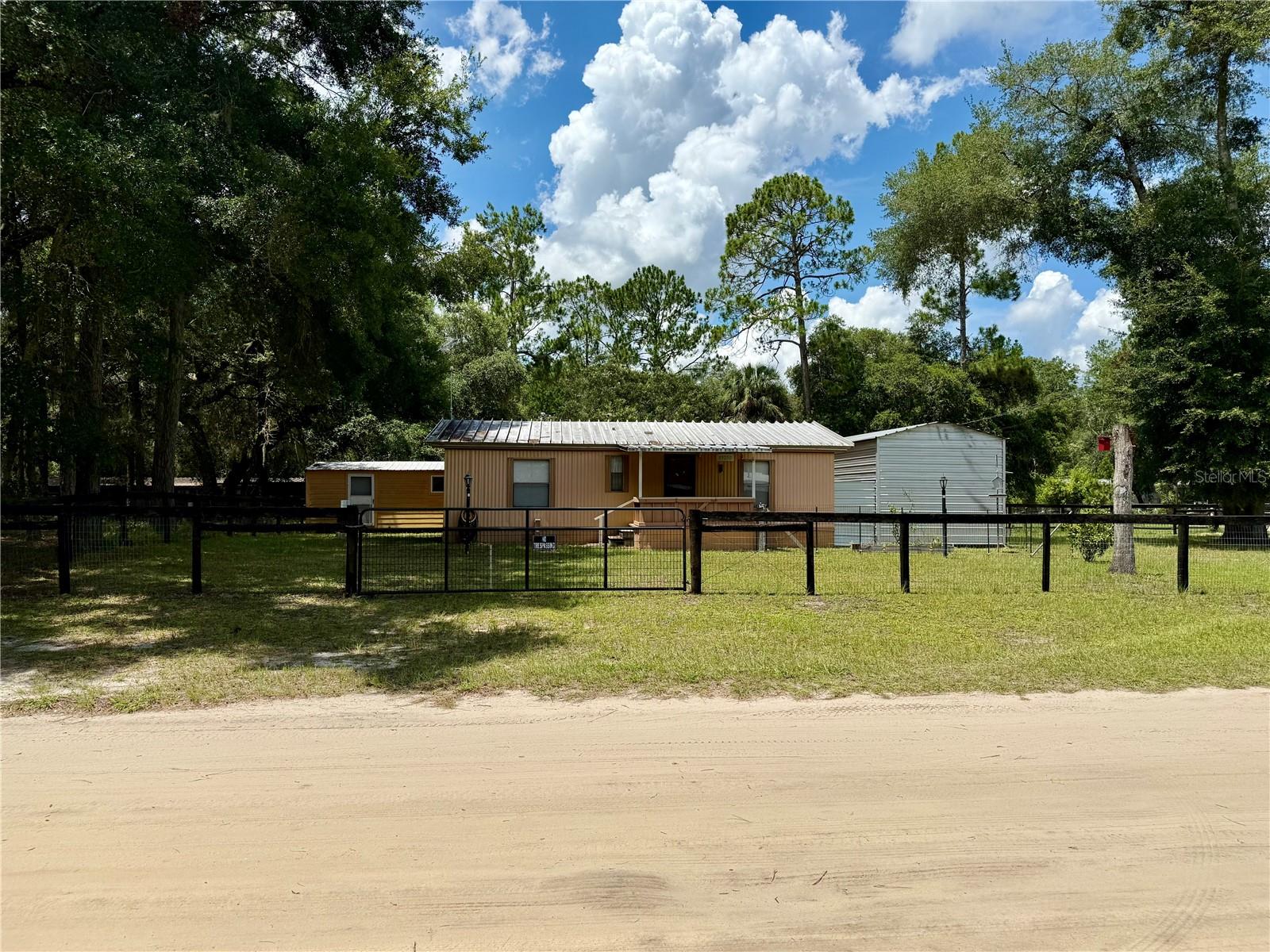 Welcome to this versatile 2-bedroom, 2-bath manufactured home in the heart of Fort McCoy, perfectly situated on a quarter-acre lot just minutes from shopping, dining, and everyday conveniences. This property combines comfortable living with unique features that make it truly stand out.
The main home offers a spacious living area with plenty of natural light, a well-laid-out kitchen with generous cabinet space, and a dining area that flows seamlessly for everyday living or hosting. The large covered back porch extends your living space outdoors, creating the perfect spot for morning coffee, evening relaxation, or weekend gatherings.
Beyond the main home, the backyard features a charming tiny home complete with its own full bathroom and kitchenette—perfect for guests, extended family, or creative uses such as a private office or studio.
A large powered workshop with lighting and a roll-up garage door adds even more versatility, giving you space for projects, hobbies, storage, or running a small business.
Located less than five minutes from local shops and services, and within easy reach of the Ocala National Forest, this property offers a peaceful setting with quick access to modern conveniences. Whether you’re searching for a comfortable primary residence, a weekend retreat, or a property with multiple living and workspace options, this Fort McCoy gem delivers flexibility and endless possibilities.