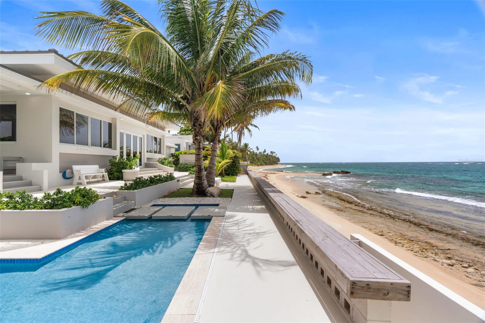 This exquisite 5-bedroom, 6-bathroom beach home offers a rare opportunity to live steps from the sand in one of Puerto Rico’s most serene coastal enclaves, located just 15 minutes from Dorado Beach.
Set on a 0.26-acre lot with direct beach access, the property blends comfort, style, and durability in every detail. With approximately 3,000 square feet of interior space and soaring 20-foot ceilings in the main living area, the home feels expansive and filled with natural light, offering breathtaking views of the ocean and coastline.
The layout is designed for both relaxation and entertaining, featuring a heated pool, an outdoor BBQ area, and two outdoor showers, one of which is connected with hot water.
A separate detached room with its own bathroom provides a flexible bonus space to use as a home office, creative studio, or guest suite. The home also includes a garage with an integrated workspace ideal for hobbies or additional storage.
Engineered for resilience and self-sufficiency, the property is equipped with a 12 kW generator powered by an 800-gallon propane tank, a 20 kW battery system, solar panels, and a 1,000-gallon water cistern. The standing seam metal roof, built with 22-gauge steel, offers exceptional hurricane resistance. Impact-resistant windows and doors—an upgrade valued at $75,000—were installed to enhance storm protection and are approved for hurricane standards by Miami-Dade County.
Surrounded by nature’s beauty as well as lush landscaping, the home exudes a unique charm that’s hard to find. With straight access to the beach, high-end finishes, and modern systems throughout, this is a true coastal gem, and the seller is open to accepting Bitcoin, making this a rare and flexible opportunity for discerning buyers seeking an extraordinary lifestyle in Vega Alta.