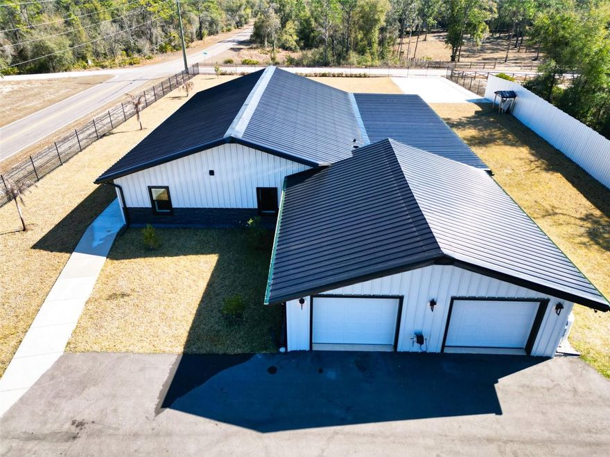 This distinctive 2025 custom-built, new-construction barndominium offers a rare blend of durability, comfort, and modern design. Constructed with red-iron framing and a 26-gauge commercial metal roof, the home offers approximately 3,800 sq. ft. under roof (NOT including the garage) and makes a strong first impression. 3 Bedroom 2-1/2 baths. Built for year-round efficiency, the home features closed-cell spray foam insulation, keeping the attic cooler even during Florida’s warmer months. Inside, you’ll find metallic epoxy flooring throughout, 18’ cathedral ceilings with walnut trim, and ceiling fans in every room. The open-concept kitchen, living, and dining area is designed for both daily living and entertaining. The kitchen includes granite countertops, a 48” ZLINE gas range with eight burners and a griddle, 48” commercial hood, GE Café appliances with gold trim, custom cabinetry, and a dedicated coffee bar. Let's not forget that the home also includes an office space.  An oversized 8’ entry from the garage leads into a spacious mudroom with generous cabinetry and storage. The guest bath is thoughtfully designed and includes a smart bidet toilet with a heated seat and a night light. At the rear of the home, a 34’ x 18’ flex room with Supra Impact sliding doors provides flexible living space and easy access to the outdoors. The versatile flex room is equipped with 3 mini split heat pump systems. Bonus Room offers flexible use as a 4th bedroom, home gym or a game room. The primary suite features a 19’x 15’ space with 12' high ceilings and a custom walk-in closet with built-in storage. The primary bathroom offers a Jacuzzi tub, porcelain walls, and a walk-in shower with gold accents. Additional features include a commercial tankless water heater, dual 4-ton heat pump HVAC units, a 22KW generator, and one 120-gallon propane tank. The exterior is professionally landscaped with St. Augustine grass and irrigation. Along with the 30’ x 30’ insulated two-car garage, the property also offers 50’x 50’ and 30’x 70’ concrete slabs, ideal for RV parking, boat storage, or outdoor entertaining. The entire property is enclosed by a 6’ galvanized steel fence and welcomes you through an impressive 20' decorative entry gate, leading to a paved driveway, plus an additional gated entrance from the side road for convenient secondary access. This is a thoughtfully designed home that stands apart from typical construction. Never occupied, this exceptional home invites its first owners to enjoy a truly pristine living experience from day one. A home this special deserves its first story let it be yours. Schedule your private showing today. Bring an offer!!!