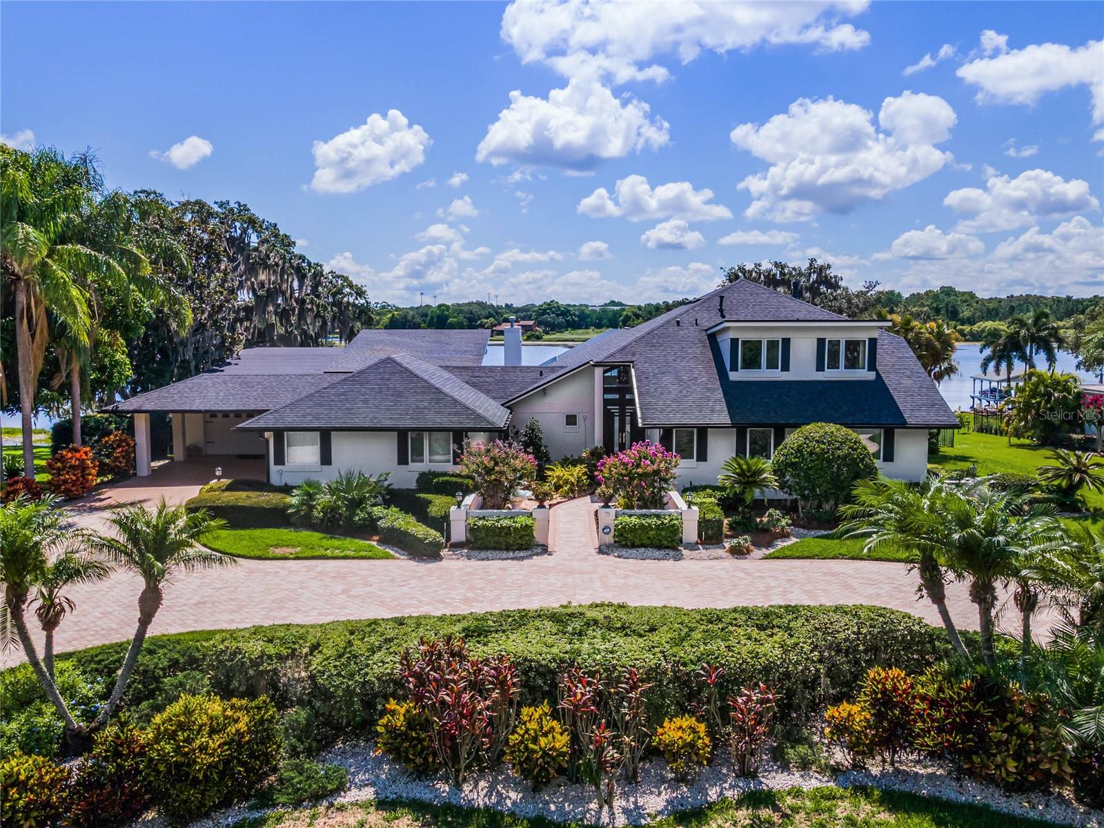 PRICE IMPROVEMENT *** Up to $25,000 in Buyer Closing Cost CREDIT Available with Preferred Lender! *** Inquire for further information *** Awake to awe-inspiring sunrises from this unparalleled lakefront estate on LAKE DOWN, nestled within the renowned BUTLER CHAIN of LAKES. Experience the tranquility and exclusivity of Sunset Bay without the burden of HOA fees. Upon entry, be captivated by soaring ceilings and breathtaking lake views. This magnificent screened-in POOL home offers over 150 feet of lakefront and spans three floors, featuring 5 bedrooms, 4 baths, an expansive living room with stunning lake views, three garages, a BASEMENT, office, formal dining room, and a versatile bonus area with a kitchenette, ideal for a guest suite and game room. The estate boasts 3 fireplaces, a fenced yard, a private boat DOCK suitable for two boats and two jet skis, as well as a sundeck for added enjoyment. The main floor encompasses the gourmet kitchen, dining area, three bedrooms, two baths, two sets of collapsible sliders opening to a covered patio, French doors, and an oversized laundry room. Just a few steps down from the main level is the elegant living room, complete with a bar and additional storage. Remote-controlled hurricane shutters ensure safety and security in the living room. The kitchen is designed for entertaining, with an open layout that perfectly complements the home's ambiance. Upstairs, discover the office and the grand primary suite, featuring a spacious walk-in closet, dual vanity, a tub, shower, fireplace, and a screened-in patio with French doors. The lower level invites you to explore the basement, an additional bedroom, a pool bath, and the bonus area with a full kitchen, all with access to the pool and backyard. This section of the home would be perfect for guests or arranged as an IN-LAW suite. Outside, indulge in the covered entertainment space or relax in the HEATED pool, complete with a sun shelf and jets. One of the garages includes an air-conditioned workshop (~10x8) and the second garage is oversized (~23x31). The third garage, located under the living room, is equipped with a roll-up hurricane shutter and is perfect for storing small trailers, boat supplies, kayaks, and paddle boards. The front of home has an inviting courtyard where you can enjoy your favorite flowers. Recent updates include a NEWER ROOF (2021), exterior paint and shutters (2021), a newer AC and water heater (2022 & 2024), screen enclosure (2016), and cool decking on the main level patio. The Butler Chain of Lakes, comprising 13 lakes, is celebrated for its pristine water quality and excellent fishing, as well as its popularity for boating and water sports. Lake Down alone spans around 900 acres, forming approximately 18% of the Butler Chain. Enjoy endless waterways for your sunset cruises. Sunset Bay is strategically located across from Isleworth and just minutes from downtown Windermere, Dr. Phillips' Restaurant Row, theme parks, golf courses, shopping, dining, and more. This lakefront gem offers limitless possibilities. With a touch of creativity and design, you can transform this estate into a masterpiece. Schedule your tour today and turn this dream home into your reality! ** Property video, 3D walk-through and a floor plan are available for this listing. **
