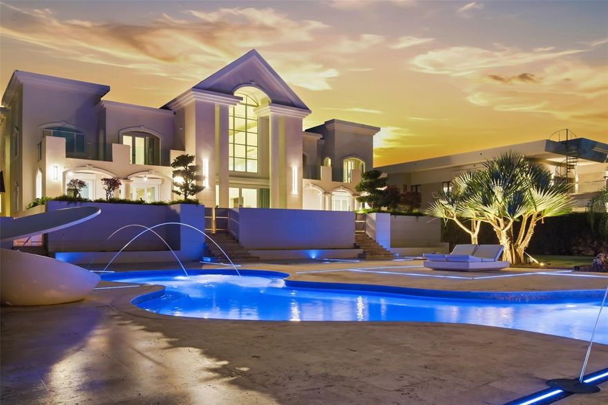 A Landmark Estate on Orquídea Street in Santa María.

Set on one of Santa María’s most desirable streets, this distinguished estate occupies over one acre of impeccably landscaped grounds, offering a level of scale, privacy, and architectural presence that is exceptionally rare in San Juan.

Approached through an opulent motorcourt, the residence rises with quiet authority. A grand façade, framed by classical columns and symmetrical lines, introduces approximately 9,500 square feet of refined interior living, where double-height ceilings and expansive proportions define every arrival.

The home is designed as both a private retreat and a destination for entertaining. Formal and informal living areas flow effortlessly, anchored by a chef’s kitchen, a spacious family room with dry bar and media wall, a dedicated cinema, wine room, pool room, and private office—each space thoughtfully positioned to balance elegance with comfort.

Outdoor living unfolds on a true estate scale. Manicured lawns frame a resort-style swimming pool, expansive terraces, and grand balconies overlooking the grounds. An outdoor kitchen and deck create a natural gathering point for entertaining, while a half basketball court adds a lifestyle-driven dimension rarely found in homes of this caliber.

Multiple levels are seamlessly connected by a private elevator and dumbwaiter, enhancing everyday functionality without compromising the home’s formal character. Expansive bedroom suites offers privacy and tranquility, completing a layout designed for multigenerational living or extended stays.

This is a residence for those who value architectural presence, generous proportions, and enduring quality—a true Santa María estate that stands apart for its scale, setting, and sense of permanence.