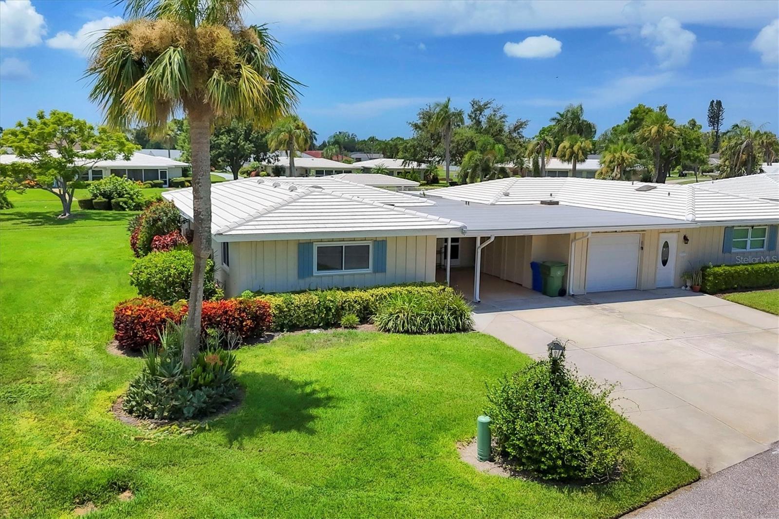 Experience the Florida lifestyle in far West Bradenton’s Village Green Condominium Association, a 55+ maintenance-free community just 5.5 miles from Holmes Beach on Anna Maria Island. This charming fully furnished and move-in-ready condo villa offers a perfect blend of comfort and convenience as a full-time residence, a lock and leave seasonal escape, or a smart investment. Having an open flowing floor plan really does make it perfect for entertaining. This villa features two large bedrooms and two bathrooms, offering generous storage space both inside and outside for comfortable living. The covered carport comes with added storage and is proven to be easy and affordable to add a garage door, just like the neighbor. The kitchen features an island workstation incorporated with more storage and a desirable openness to the living, dining and family room making communication a delight. Extra cabinets, a panty, laminate flooring and new in 2025 a Stainless Steel GE appliance package. The indoor laundry room features full size washer and dryer, a utility sink and a closet full of storage cabinets. For easy maintenance, newly installed vinyl plank flooring runs from the foyer through to the living, dining then to the Florida room. The two bedrooms still feature carpet and baths are tile. Both electric couches in the living room were just purchased. Multiple lights, fans and fixtures have been modernized. The baths have original vanities yet are super clean and presentable. The exterior windows are now double-pane insulated and energy efficient for year-round comfort. The 21 x 8.5 Florida room under air offers an abundance amount of extra living space for lounging and entertaining. The private outdoor 12 x 12.5 concrete patio is perfect for morning coffee or evening wine. The relaxing view consists of a well-maintained greenbelt in a park-like setting with a sidewalk just out the back door leading to the large community heated pool, dedicated only to Cluster 2. The tile roof 9/2008, flat roof 11/2022, A/C manufacturing date 7/2013, and the 40 gallon HWH 2023. You can have an inside cat, no dogs and no renting. All conveniently located to all of your personal needs, Holmes Beach, Bradenton Beach, GT Bray Park, Robinson Preserve, Downtown Riverwalk, SRQ Airport, and essential amenities. Sold AS IS with right to inspect.