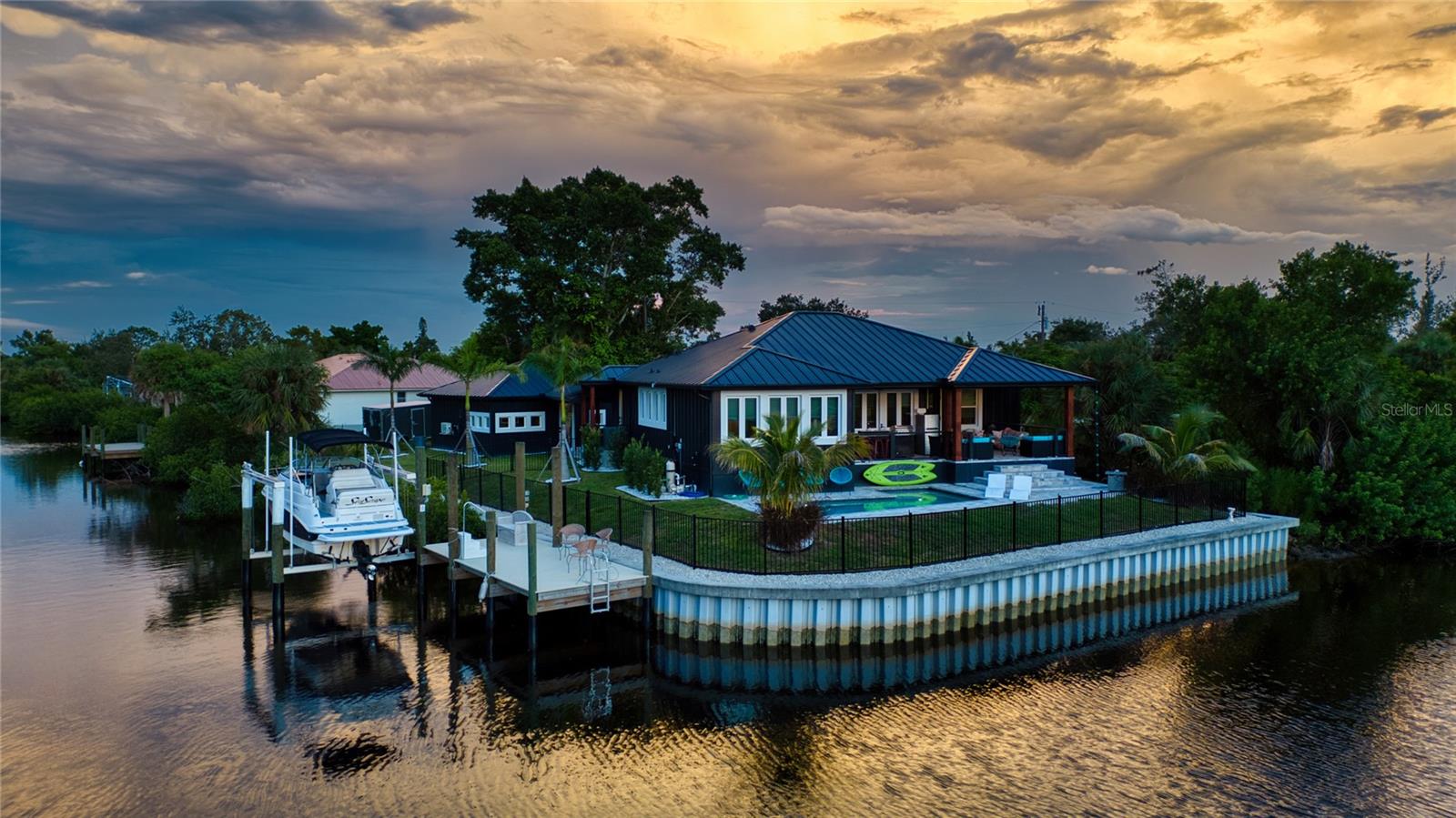A One-of-a-Kind Masterpiece on the Water! Welcome to 3001 Banyan Way, Punta Gorda, completed in 2024, where architectural artistry meets uncompromising luxury. Set on a prime waterfront lot with intersecting canal views, 211 feet of seawall, and remarkable sunsets, this bespoke residence was crafted with every imaginable upgrade to create a true designer dream home. Simply stunning! From the moment you arrive, the curb appeal is undeniable— ultra modern and powerful exterior colors inspire the senses. A visual delight are the many exterior accents including Hardi Trim Board and Batten cement siding, an expansive lighted retaining wall, offset garage and connecting breezeway with smart wood beam pillars. Professional landscaping with designer lighting, an interlocking three-piece paver driveway and an iron fence with three locking gates frame the back of the property all the way to the seawall. Step onto the Chicago replica brick front porch, beneath a tongue-and-groove ceiling with recessed lighting, and through an impressive iron entry door. Inside, every room tells a story of craftsmanship and indulgence. The living room stuns with Venetian plaster tray ceilings, dramatic beams, a 100-inch linear fireplace, and a full quartzite feature wall. The gourmet kitchen is a showpiece: Dolomite Blue quartzite countertops throughout, GE Café matte white appliances including a six-burner propane range, two under-counter refrigerators, and full-height subway tile with a quartzite shelf. A walk-in pantry and adjoining laundry doubles as a bar and prep space, featuring cobalt blue GE smart appliances, built-in storage, a liquor drawer, and a chandelier-lit window seat. The master suite is a sanctuary with Venetian plaster finishes, custom ceiling design, and a spa-like bath offering a freestanding tub under chandelier light, a walk-through shower with body jets, double marble sinks, and artistic feature walls. Additional rooms showcase true individuality, including a music room adorned with gold-leaf stucco, a bespoke feature wall, and a dramatic chandelier. Outdoor living reaches resort level. A saltwater, heated PebbleTec pool with LED lighting is surrounded by an expansive paved entertainment deck. The covered rear porch features tongue-and-groove ceilings, an outdoor kitchen with grill and sink, recessed lighting, ceiling fans, and dual French iron doors that invite seamless indoor/outdoor living. At the water’s edge, the composite dock is built for the serious boater, with shore power, a 12,000-lb lift, and oversized pilings ready for a roof structure. Enjoy a 15 minute boat ride along the Venice Waterway to Alligator Creek, then to Charlotte Harbor and the Gulf beyond. Every detail is deliberate: spray foam insulation throughout, tankless water heater, hurricane-impact doors and windows, remote custom blinds, lighting integrated into the eaves and landscaping, the highest grade luxury vinyl plank and soap stone tile flooring, and a full-home generator with hook-up. The oversized 24’x24’ insulated garage is a marvel in itself, with epoxy floors, mini-split A/C, EV plug, storage system, and large windows framing canal views. This residence is more than a home—it’s a statement of taste, design, and lifestyle. Perfectly blending Old World materials with cutting-edge systems, 3001 Banyan Way is truly one of a kind Gem. Minutes from all that Punta Gorda has to offer, Fisherman’s Village, Harbor Walk, the Punta Gorda Yacht Club, and so much more!
