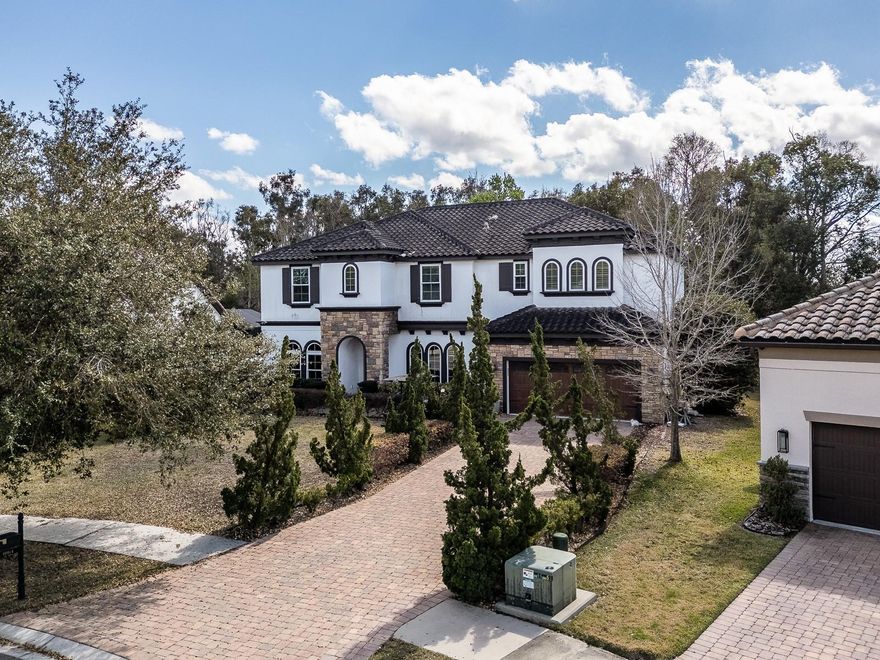 Architectural elegance meets resort-style living in this beautiful home located on a quiet tree-lined street in the highly desirable Lake Magdalene / Carrollwood area of Tampa with no HOA or CDD. From the moment you arrive, the home makes a striking impression with its tile roof, custom wood front door, custom garage door, brick paver driveway, and extended paver front porch sitting area. Step inside to soaring ceilings, architectural lighting, elegant herringbone-pattern tile flooring, custom stone accents, and a dramatic floating staircase with glass railing that creates an unforgettable first impression. The kitchen anchors the main living space and features granite countertops, stainless steel appliances, double wall ovens, a walk-in pantry, and a large shiplap-accented breakfast bar overlooking the open living and dining areas. The spacious primary suite offers a relaxing retreat with a large walk-in closet. The expansive spa-inspired primary bathroom creates a true retreat within the home, featuring floor-to-ceiling tile, dual rainfall showers with glass enclosures, generous vanity space, and a freestanding soaking tub positioned between the showers, creating a dramatic and luxurious spa-like setting. Upstairs, the thoughtfully designed layout includes three additional bedrooms, a spacious loft area ideal for a media room, office, or playroom, and a conveniently located laundry room, keeping all bedrooms and laundry on the same level for everyday ease and functionality. Step outside to your private backyard oasis with a custom pool with water features, expansive stone pool deck, and peaceful conservation views. The screened lanai features tiled flooring, exterior ceiling fans, and an outdoor summer kitchen with sink and refrigerator, perfect for Florida outdoor living and entertaining. Additional features include an in-wall pest control system, ADT security system, hurricane shutters, UV HVAC air sanitizing system, custom garage shelving, and a premium lot setback offering additional privacy. Conveniently located just minutes from downtown Tampa, Tampa International Airport, and an abundance of shopping and dining options, this home offers a rare combination of thoughtful design, extensive upgrades, and an exceptional location.