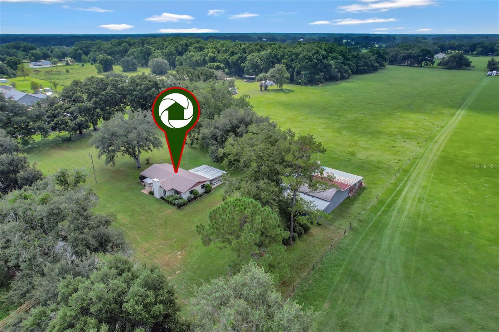 Private & peaceful this 10-acre Ocala homestead sits in the desirable Hwy 475 corridor offering a quiet country setting just minutes to city conveniences. Eight acres of lush, high and dry pastures are ready for horses, cows, goats, while the remaining acreage provides a charming backdrop for the 3BR/2BA home. Property features include a 30’x15’ enclosed garage, 40’x40’ pole barn, 40’x21’ shed row/lean-to, and multiple fruit trees. Inside, enjoy terrazzo floors, a stone fireplace, spacious dining area, galley kitchen, and a large covered patio overlooking the land. Just 27 minutes to the World Equestrian Center, near The Villages, Greenway Trails, and the Florida Horse Park this is the perfect retreat for equestrians, hobbyists, or anyone seeking space, privacy, and endless possibilities.