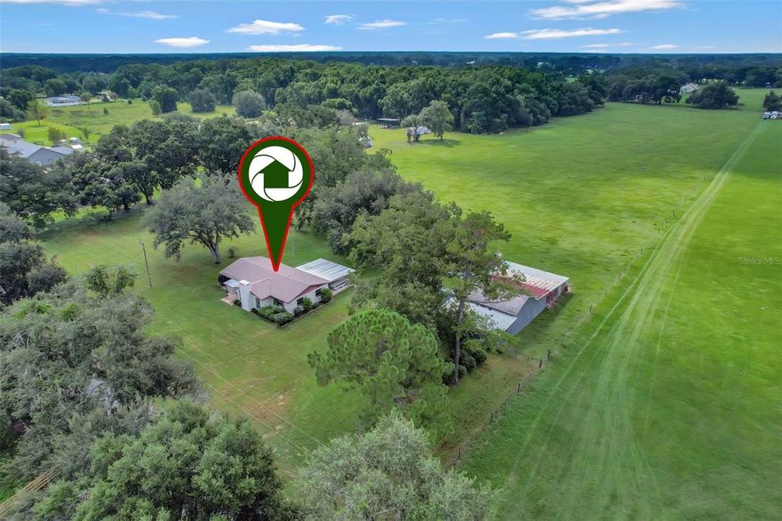 Private & peaceful this 10-acre Ocala homestead sits in the desirable Hwy 475 corridor offering a quiet country setting just minutes to city conveniences. Eight acres of lush, high and dry pastures are ready for horses, cows, goats, while the remaining acreage provides a charming backdrop for the 3BR/2BA home. Property features include a 30’x15’ enclosed garage, 40’x40’ pole barn, 40’x21’ shed row/lean-to, and multiple fruit trees. Inside, enjoy terrazzo floors, a stone fireplace, spacious dining area, galley kitchen, and a large covered patio overlooking the land. Just 27 minutes to the World Equestrian Center, near The Villages, Greenway Trails, and the Florida Horse Park this is the perfect retreat for equestrians, hobbyists, or anyone seeking space, privacy, and endless possibilities.