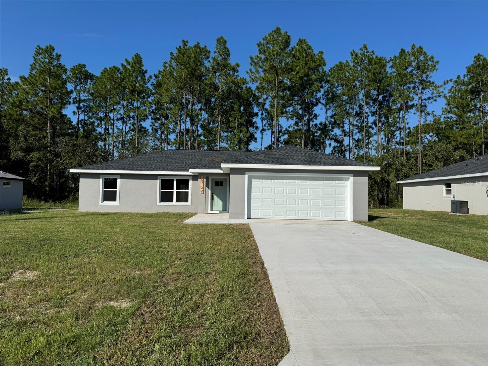 Welcome to the 1400 model, located in the desirable North side of Marion Oaks. This thoughtfully designed home offers spacious living with a split floor plan and conveniently backs up to a non-buildable tree line providing privacy from rear neighbors.
The owner's suite features a tray ceiling, lighted ceiling fan, a generous walk-in closet, and a stylish en-suite. The master bath features a dual sink vanity, and a tiled walk-in shower surrounded by a sleek frameless glass enclosure, and a linen closet. Guest bedrooms and a full bath are situated on the opposite side of the home, ideal for family or visitors. The kitchen is a true centerpiece, featuring a large island perfect for meal prep and casual dining, abundant solid wood cabinetry with soft-close doors, granite countertops, a pantry for added storage and convenience, and completed with top of the line GE appliances. Both the kitchen and bathrooms reflect quality craftsmanship and timeless style.
Luxury vinyl tile flooring extends throughout the home, providing low-maintenance durability. Additional features include a well-appointed interior laundry room complete with a linen closet and brand-new front loader GE washer and dryer, a generously sized two-car garage for added convenience, and a hard to find standard septic system - not an aerobic septic system! This home is ready to welcome its first owners!