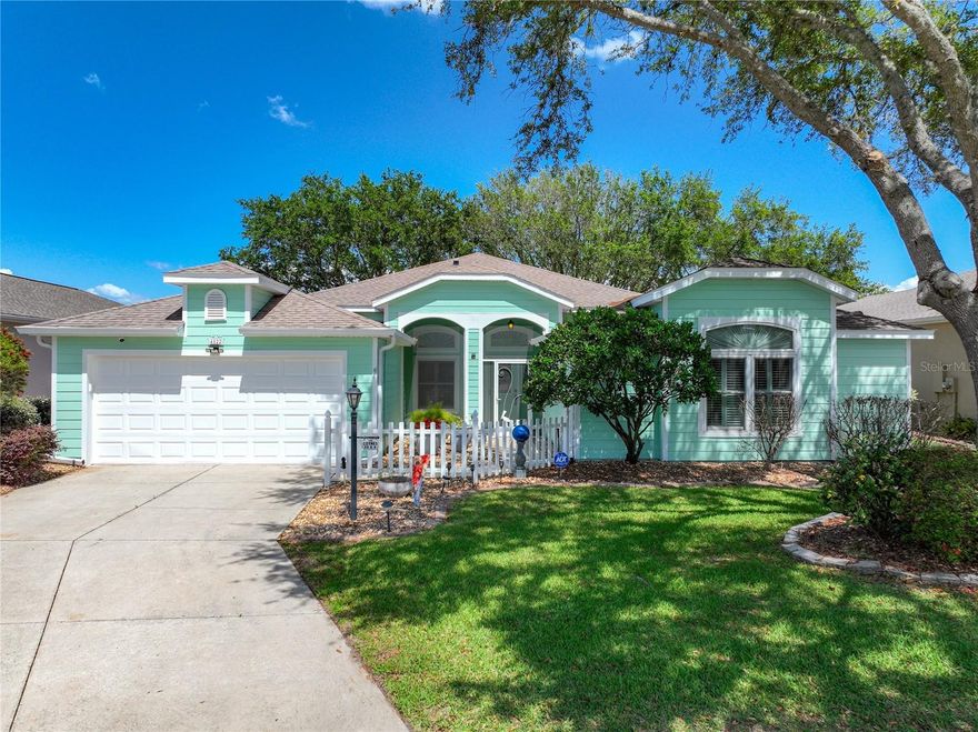 Experience elevated Florida living in this exceptional home perfectly positioned above the third tee box, offering breathtaking panoramic views of the golf course, Sawgrass Lake, and The Manor clubhouse. From the moment you arrive, a screened front entry welcomes you into a residence filled with elegance, space, and natural light. One of the home’s most distinctive features is the stunning library, showcasing floor-to-ceiling custom oak shelving and rich hardwood flooring—an ideal retreat for book lovers or a sophisticated home office. This highly desirable floor plan offers 3 bedrooms, 3 bathrooms, and 2,780 square feet of thoughtfully designed living space. The expansive living and dining areas feature soaring ceilings, beautiful hardwood floors, and seamless flow—perfect for both everyday living and entertaining. Enjoy captivating evening views of the illuminated clubhouse across the lake from the living room and the inviting Florida room, which provides additional living space with large windows and direct access to one of two patios. The spacious kitchen is bright and airy with cathedral ceilings, abundant cabinetry and counter space, a large pantry, and a cozy breakfast nook. Glass doors lead to a screened patio complete with a water-resistant shade canopy, allowing you to relax and take in the spectacular scenery year-round. The oversized primary suite is a true retreat, featuring a massive walk-in closet, updated vinyl flooring, and a luxurious en-suite bath with a Jacuzzi tub, dual vanities, and an oversized, handicap-accessible walk-in shower. Guest accommodations are thoughtfully positioned at the front of the home, offering privacy with a full bathroom, generous closet space, and a versatile third bedroom equipped with a Murphy bed. Curb appeal abounds with beautifully maintained landscaping, brick-lined flower beds, a manicured lawn, and a full irrigation system. This home has been meticulously maintained and updated, including a new HVAC system (2024), a 50-year shingle roof (2017), plantation shutters, hardwood flooring, gutter guards, and durable HardiPlank siding. Additional highlights include dual-paneWindows in  golf ball-resistant windows, an extended garage, and a new ADT security system with exterior cameras and dual control panels. Located in the sought-after Plantation at Leesburg, residents enjoy resort-style amenities including two golf courses, three clubhouses, pools and spas, fitness centers, tennis, pickleball, bocce, a driving range, on-site dining, and countless social activities. Conveniently located less than an hour from Orlando International Airport and within easy reach of both Florida coasts, this premier gated 55+ community offers the ultimate in lifestyle and convenience. This remarkable home truly has it all—luxury, comfort, and unforgettable views.