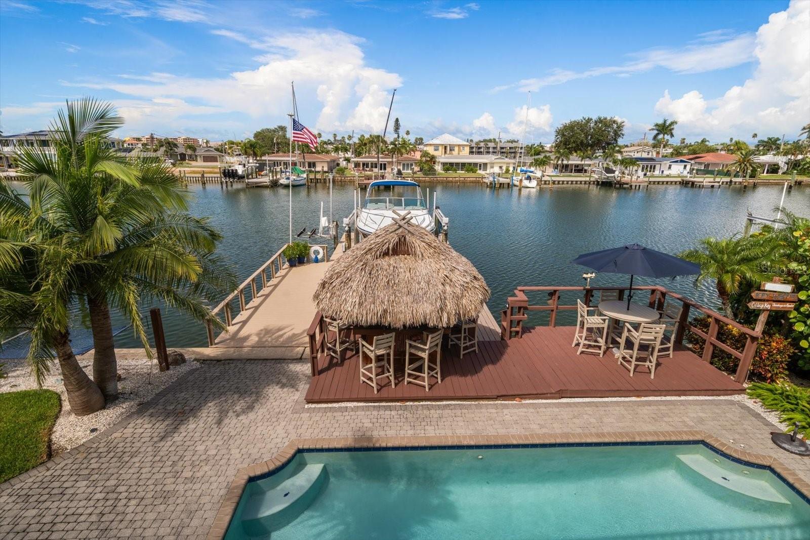 WELCOME TO YOUR WATERFRONT COASTAL PARADISE! This remarkable 5-bedroom, 3.5-bath waterfront home offers over 4,000 square feet of luxury living, blending timeless design with modern features for the ultimate Florida lifestyle. From the moment you arrive, the coastal metal roof installed in 2019 and grand entryway set the tone for the elegance within. Inside, you’ll find expansive living spaces highlighted by two fireplaces—one in the inviting living room and another in the private primary suite. The chef’s kitchen opens seamlessly to spacious dining and gathering areas, making it ideal for entertaining family and friends. The primary suite completely remodeled in 2021 is a sanctuary, featuring its own fireplace, spa-inspired bath, and a private top-floor terrace where you can watch spectacular Gulf Coast sunsets. Additional bedrooms are generously sized, and the dedicated office provides the perfect work-from-home space. A game room ensures endless fun, while the thoughtful floor plan creates harmony between everyday living and entertainment. Two new air conditioner systems installed in 2019 and two new water heaters in 2022. Outdoors, your private paradise awaits. Enjoy a refreshing swim in the heated salt water pool with a new pump installed in 2025 and salt generator. You also can take advantage of the 20,000LB boat lift and updated double-sided dock for effortless adventures on the water. With a 4-car tandem garage, there’s room for all your vehicles, toys, and storage needs. Exterior completely painted in 2023. This home was designed for those who love to gather, celebrate, and live life to the fullest. Every detail of this home was crafted for connection and celebration—whether gathering around the fire on cool evenings, hosting sunset soirees on the terrace, or enjoying quiet mornings watching dolphins play in the bay. This is more than a home; it is a lifestyle, a statement, and a legacy. Call for your private showing today!