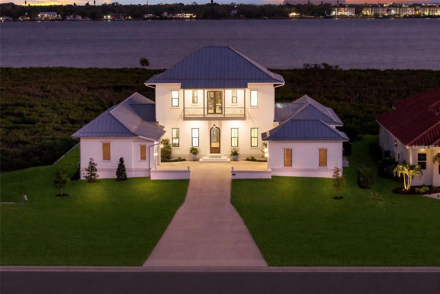 A TRULY EXCEPTIONAL NEW CUSTOM BUILT WATERFRONT ESTATE ON THE MANATEE RIVER WITHIN THE PRESTIGIOUS GATED ENCLAVE OF WATER'S EDGE AT SANCTUARY COVE! Uncompromising craftsmanship and sweeping panoramic water views create an extraordinary  residence. Designed with inspiration from the Coastal Living Idea House by Cooper Johnson Smith Architects, this remarkable home offers a rare blend of refined craftsmanship, resort-style outdoor living, and direct boating access, creating an unparalleled Florida lifestyle defined by elegance, comfort, and effortless indoor-outdoor living.
Perfectly positioned to capture sweeping water views from the front, rear, and side elevations, the home includes a 35-foot private boat slip with a 10,000 lb lift, complete with water and power. Built with lasting quality in mind, this home features a standing seam metal roof, half-round galvalume gutters, a closed attic system and spray foam insulation throughout the second floor. Interiors are finished with level 5 smooth drywall, engineered oak hardwood flooring throughout, and extensive custom millwork and casework. Architectural details include custom door surrounds, transoms in the living room, cove molding, and LED-accented coastal molding in the family room and kitchen. Ceiling heights impress with 12-foot ceilings along with vaulted ceilings in the kitchen, family room, porch, and primary suite.
The chef’s kitchen is designed for both function and entertaining, featuring high end cabinetry, a custom chateau style range hood, granite countertops with warm neutral tones, a one-piece granite island with seating for five, banquette seating, an 8-burner gas double oven range, warming drawer, and under-cabinet and cove lighting. The kitchen flows seamlessly into the family room and screened porch, enhancing the home’s open-concept design.
A well-appointed laundry and utility space offers quartzite countertops, a full pantry, laundry sink with cabinetry, hanging space, and additional linen storage. The primary suite is a private sanctuary with a vaulted ceiling, motorized blackout shades and a private terrace with full river views. The spa-inspired bath features marble finishes, double sinks, basketweave tile detailing, marble wainscoting, and a multi-head shower system with rainfall, waterfall, and body sprays, along with thermostatic controls and a heated towel rack. The suite also connects to a private courtyard with a fountain and outdoor shower.
Outdoor living is equally impressive with a heated and cooling saltwater pool and spa. The exterior showcases a herringbone brick driveway, golf cart parking, and distinctive copper gas lanterns at the front entry and screened porch.
Modern efficiency and technology include a whole-house natural gas generator, two tankless gas water heaters and smart LED lighting.
This extraordinary residence offers a rare opportunity to own a meticulously designed waterfront home that seamlessly blends architectural excellence, luxury finishes, and premier boating access in one of the area’s most desirable coastal communities.  This home offers convenient access to the 365 acre Emerson Point preserve, the beaches of Anna Maria Island, local restaurants and two nearby airports. Embrace the beauty of Florida waterfront living, where boating, sunset views and coastal relaxation are part of everyday life.