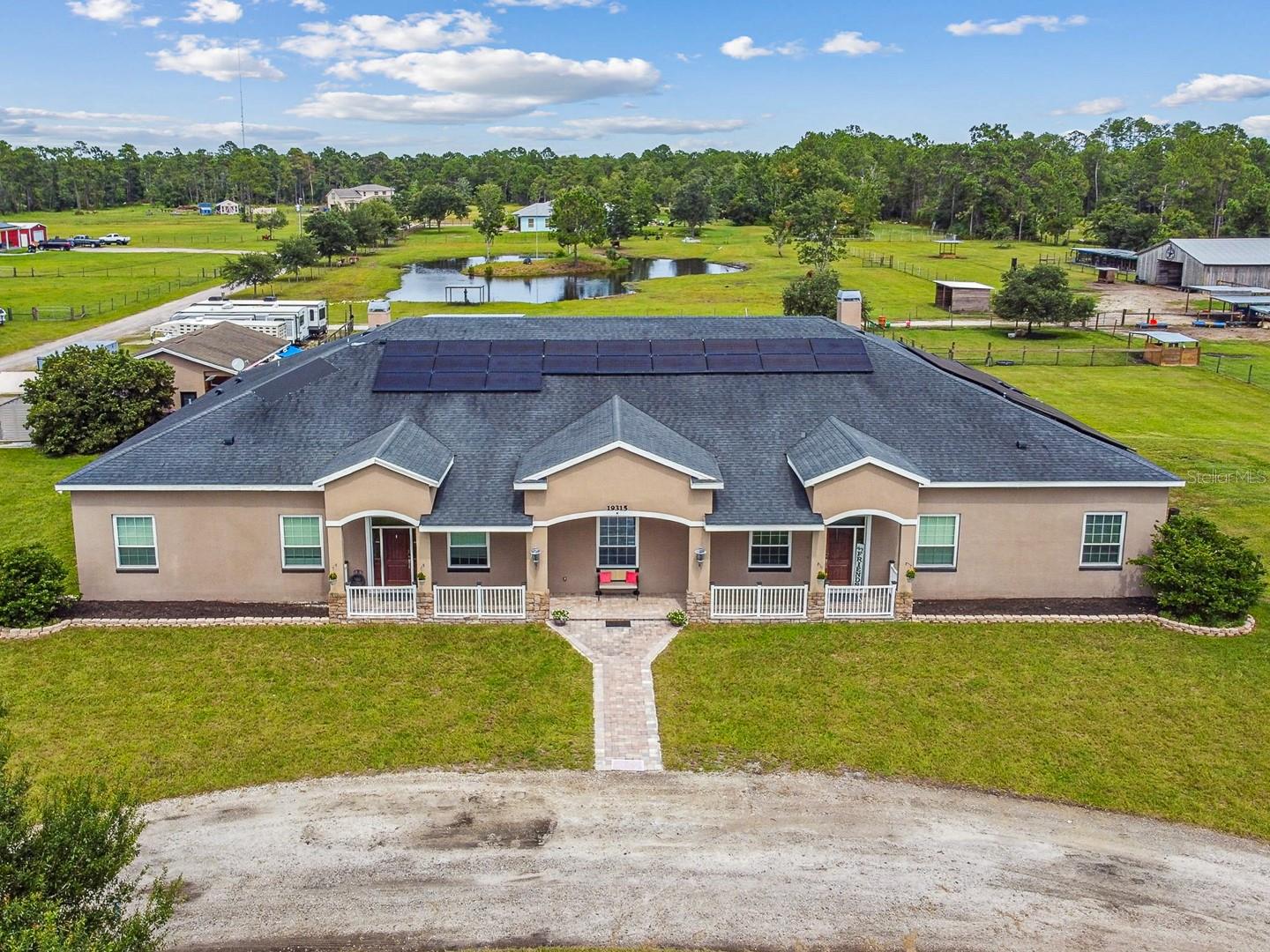 Exceptional 5.25 acre multi-generational estate now available just off of Lake Pickett Rd in Orange County, Florida. Designed with versatility in mind, this one-of-a-kind property offers 6,032 square feet of living space and features two complete residences under one roof—perfect for extended families, in-laws, or dual living arrangements. Each side of the home has its own private front entrance, full kitchen, primary suite, and living areas, creating symmetrical spaces ideal for privacy and independence. In the center of the home, a nine-seat theater room and full-size game room with a built-in bar provide the ultimate space for entertaining. The home boasts 12-foot ceilings, crown molding, two fireplaces, spacious walk-in closets, and a mix of custom finishes. One kitchen features custom cabinetry, granite countertops, and stainless steel appliances, while the second is equipped with 42-inch maple cabinets, a center island, and matching appliances. A new roof will be installed in 2025 at the seller's expense. New windows, exterior doors, and luxury waterproof vinyl plank flooring was installed in 2018. New HVAC units were added in 2023, and a new water heater was installed in 2022. Equipped with solar panels, the home supports true off-grid living without sacrificing comfort or convenience. Outside, you will enjoy a resort-style setting, highlighted by the custom-designed 50,000-gallon commercial-grade pool built in 2021. A fire pit and covered patios add to this massive outdoor entertainment space. The land is fully equipped for animal lovers and equestrian use, featuring a six-stall barn with tack room, two additional mini barns with stalls, and three feeding houses. For kennel operations or hobby breeders, there are eight outdoor dog kennels with water and electric service. The property is fully fenced and cross-fenced for multiple pastures with a new perimeter fence added in 2024. Three separate water wells supply plenty of water for the home, barn, kennels, and the irrigation system. The spring-fed pond, complete with an aerator, is a standout feature of the property. Additional highlights include a 2.5-car detached garage and workshop, an RV hookup with both 30- and 50-amp service, and no HOA restrictions! This property combines peaceful country living with the modern comforts of a thoughtfully updated estate—all within close proximity to shopping, dining, and major roadways. Rarely does a property check every box—land, location, upgrades, and space. Do not miss this opportunity!