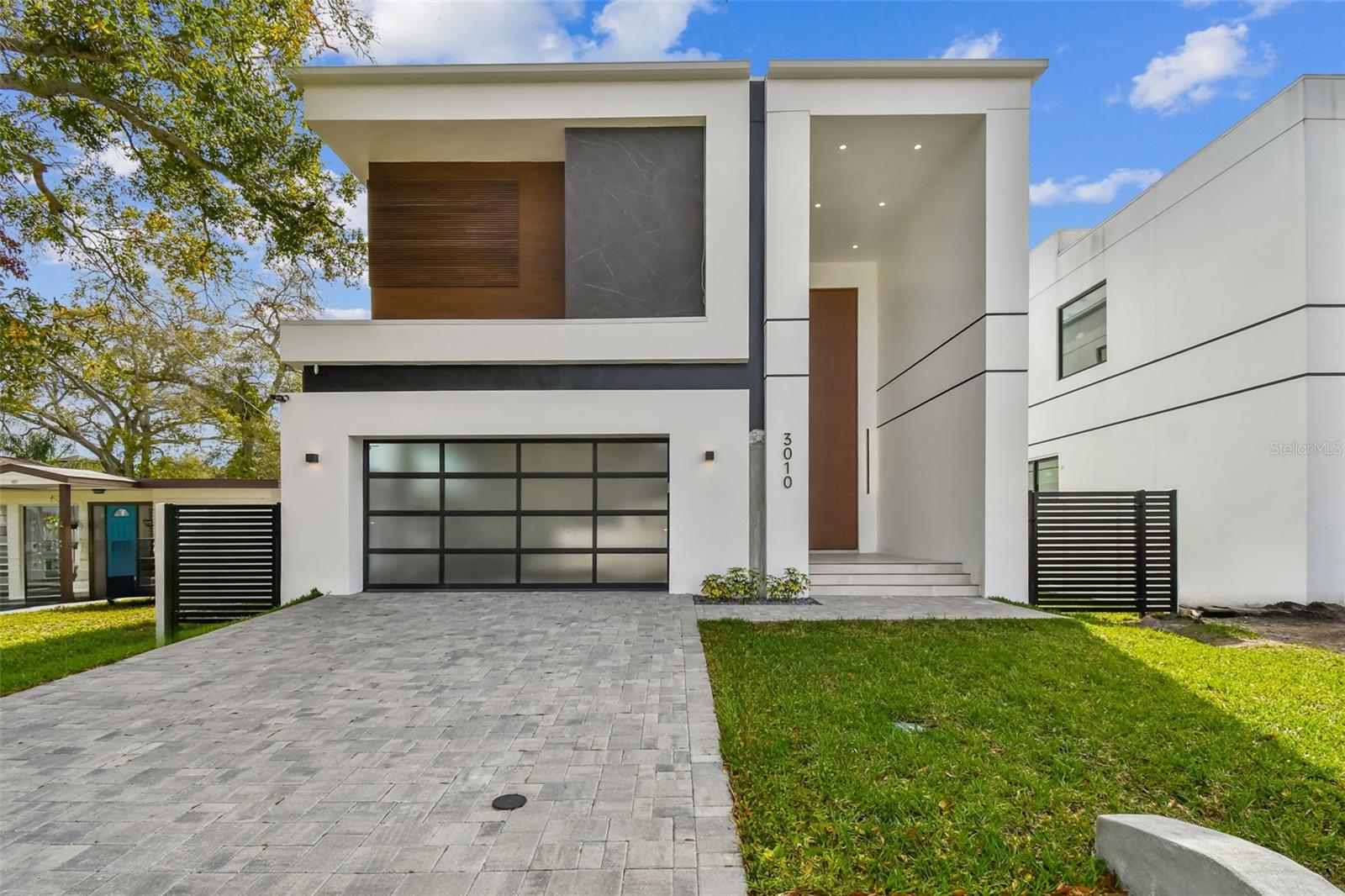 Step into the grandeur of 3010 W Trilby Ave, a true treasure nestled in the heart of South Tampa and a testament to Arjen Homes' mastery of luxury modern construction. The exterior exudes sophistication with Opel modern porcelain slabs, a distinctive frosted aluminum garage door, and an industrial-grade epoxy finish, solidifying its status as Tampa's exclusive luxury modern build. The Arjen modern style pivot door invites you into a foyer adorned with a 6’-0” wide by 20’-0” high custom imported pivot door, emphasizing the meticulous craftsmanship defining this residence. The first floor unfolds with a seamless blend of imported floor tiles, bespoke LED chandeliers, and a cutting-edge Biofuel fireplace. The kitchen is a work of art with match grain wood paneling, leathered countertops, and Kohler Stain finishes. Features electric appliances with optional gas included, with an induction stove and a discreetly paneled refrigerator, the kitchen strikes a perfect balance between form and function. The first floor also hosts a convenient half powder room/bathroom and an office, enhancing the practicality of this luxurious space. Ascending the color-matched steps to the second floor, the high ceilings continue to captivate. Three bedrooms, each with its private bathroom and upscale fixtures, precede the primary bedroom. The primary suite is a sanctuary of luxury, boasting a mini bar with a fridge, a walk-in closet illuminated by LED-lit hanger rods, and a bathroom that defines opulence. The primary bathroom is a masterpiece with floor-to-ceiling glass, a digital valve system in the shower, a ceiling-fill standalone tub, a spacious vanity, and an in-wall water closet. The property is thoughtfully designed, with a natural gas line anticipating a potential pool. The rear is adorned with bamboo along a PVC paneling fence, creating a secluded outdoor retreat with the possibility for an outdoor kitchen. This smart home features in-wall speakers, pre-wiring for security, and window shades. From the inviting front entrance to the tranquil rear oasis, this 2-story masterpiece is a testament to Arjen Homes' unwavering commitment to excellence and the embodiment of true luxury modern living.
