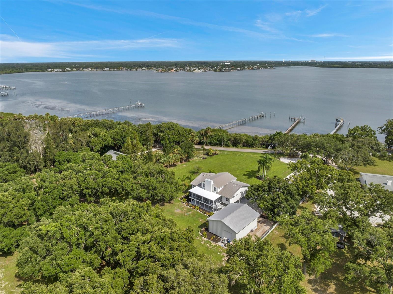 This stunning estate home offers a luxurious and serene waterfront lifestyle with space and features rarely available in the area. Located in beautiful pristine Terra Ceia, nestled on coveted Bayshore Drive, this home is a true gem for those seeking an idyllic waterfront retreat. Sitting on an oversized 2.75 acres with approximately 200 feet of water frontage, the 346 ft dock with a deep-water slip is a boater's paradise. As you step inside, you'll be captivated by the elegant and modern design that perfectly complements the natural beauty surrounding the property. The spacious open floor plan allows for seamless flow and abundant natural light, creating a warm and inviting atmosphere throughout. The gourmet kitchen is a chef's dream featuring high-end appliances, sleek countertops, and expansive views from the dining area. Whether you're hosting intimate gatherings or preparing meals for your loved ones, this kitchen is sure to inspire culinary creativity. The living area is a haven of relaxation, with large windows framing the expansive exterior. Towering, vaulted ceilings and abundant trim and stone bring the feel of a waterfront architectural gem. The master suite is a private oasis to escape to and unwind. With its own balcony overlooking the water, you'll enjoy quiet moments of tranquility. The en-suite bathroom is beautifully designed with luxurious finishes, a walk-in shower, and designer touches throughout. This property also features additional well-appointed bedrooms, each with its own unique charm and plenty of space for family and guests. The versatile layout allows for customization and flexibility to accommodate your specific needs, including a 2-bedroom mother-in-law suite with a custom designed kitchen that could be used as an Airbnb or even on-site housing for staff if you are an absentee owner! Outdoor living is a highlight of this property, as it seamlessly blends with the captivating natural surroundings. The expansive deck provides the perfect space for entertaining, with views that will leave your guests reluctant to leave. Walk across the lushly landscaped yard to your own private dock, where you can embark on boating adventures or simply relax and enjoy the soothing sounds of the water. You will also appreciate the detached 1200 sq ft building, partially air conditioned, with 14 ft ceilings and 4 large roll up doors: Boat, car, or RV storage space at its best. Terra Ceia offers a tranquil and close-knit community, known for its natural beauty and a slower pace of life. With its proximity to Tampa, St. Petersburg, and Sarasota, you'll have easy access to a variety of amenities, including shopping, dining, cultural attractions, and pristine beaches. Don't miss your opportunity to own this exceptional waterfront property. Immerse yourself in the beauty of nature, indulge in luxurious comforts, and create memories that will last a lifetime. Contact us today to schedule your private showing and experience the lifestyle you've been dreaming of