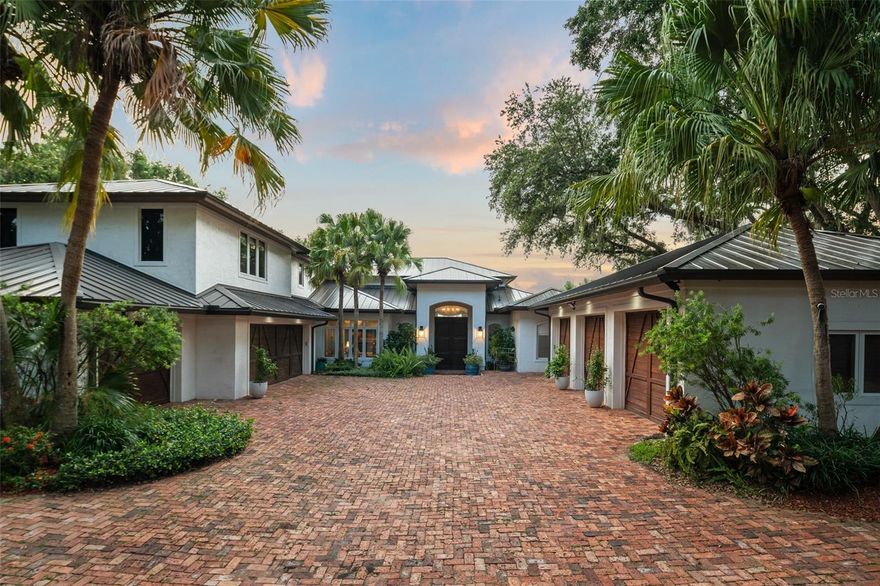 Motivated Seller - Experience refined lakefront living in this exceptional estate, ideally located within the renowned Isleworth Golf & Country Club. Set along the shores of Lake Bessie on a beautifully landscaped 0.56-acre lot, the home spans 5,557 square feet of luxurious living space. A NEW METAL ROOF in 2024 adds both modern appeal and long-term durability, enhancing the home’s overall value and aesthetic. Grand mahogany French doors welcome you into an expansive formal living room, where large picture windows perfectly frame the breathtaking lake vistas. Adjacent, the elegant formal dining room connects to a gourmet kitchen featuring smooth granite countertops, a center island with a professional-grade range and contemporary hood, stainless steel appliances, and travertine flooring. A cozy breakfast nook and inviting family room—both with stunning lake views—complete the heart of the home. Wine enthusiasts will appreciate the custom wine cellar, adorned with a reclaimed Old World wooden door and capacity for over 500 bottles. This space seamlessly connects to a richly appointed home office and trophy room, each featuring bespoke wooden built-ins. The primary suite offers a tranquil sitting area overlooking the lake, along with a luxurious en-suite bath that includes dual vanities, a garden tub, and a walk-in shower. Upstairs, three additional bedrooms accompany a home theater with soundproof walls, a built-in wet bar, and intricate wood detailing, creating the ultimate cinematic experience. Outdoors, a spacious lanai with a summer kitchen overlooks an elevated terrace, pool, and spa, perfect for entertaining or relaxing while enjoying spectacular sunsets and nightly fireworks from nearby theme parks. This rare lakefront gem blends timeless elegance with a prime location, offering an unparalleled lifestyle in one of Central Florida’s most exclusive communities.