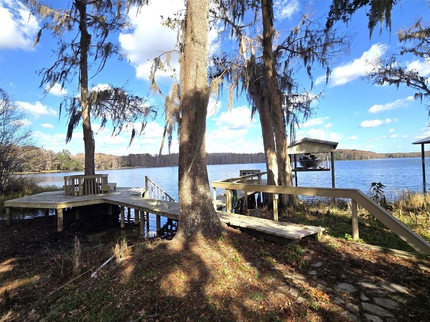 This beautiful and peaceful home is nestled on a perfect lot with Lake Church as its backdrop.  Gorgeous all day views that will make you stand and just enjoy watching nature do its thing.  This 3 bedroom 4 bath home offers 2 Primary Suites one upstairs and the other on the main level and a third bedroom on the main level for whoever needs it. The kitchen is nicely equipped with a formal Dining room as well as a dinette. 
There are amazing Lake views from multiple places in the home plus a large back deck, completely screened in with a perfect sized salt water pool to enjoy all the hot summer days and nights to go along with that ever amazing lake view.  Entertaining in this home will be easy with lots of open areas to have crowds gather comfortably. There is a dock with a sitting area and lift for your boat of which you should enjoy using it on the large relaxing lake. There is also a place to park and RV with a plug power source.
