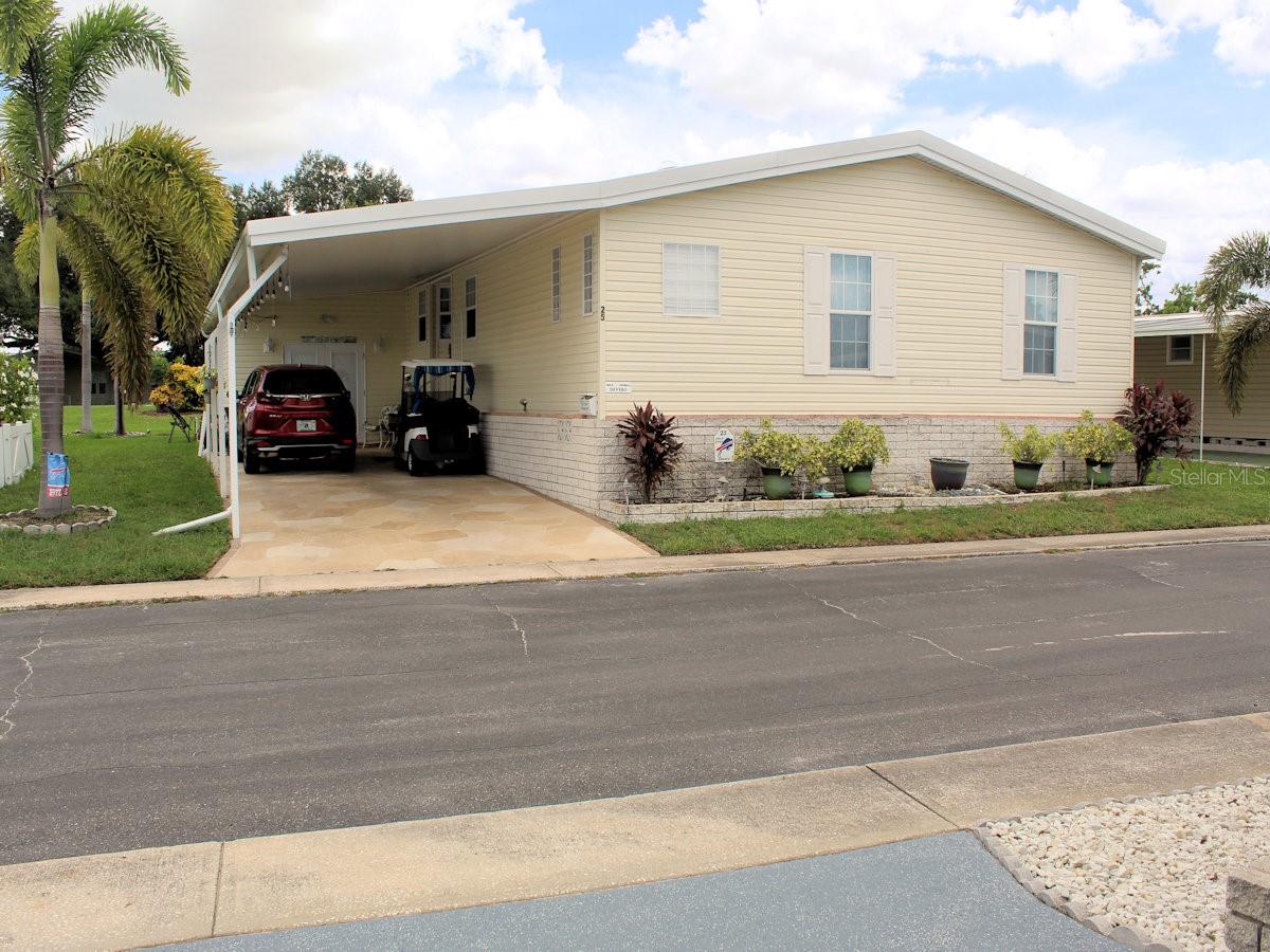 Are you looking for A Forever Home? This 2007 Jacobsen manufactured home in Palm Hill Mobile Home Park offers 1,962 heated and cooled square feet is well worth considering. It has two bedrooms and a generous size den. The property is ideally situated on Palm Hill’s golf course on the ninth tee. One monthly maintenance fee of $554 covers a lot-water, sewer, trash, recycle, lawn care, cable and internet. No one stays a stranger for long in this outstanding five-star,55+park. From pools, jacuzzies, tennis, pickleball, golf, shuffleboard, to clubhouse activities it is easy to make friends. This turnkey home has had only one owner. All walls are finished with drywall and ceilings are vaulted. It has been beautifully maintained and updated and is being sold mostly furnished. The kitchen updated in 2022 has a striking roomy island with cooktop and sitting space. Quartz countertops sparkle throughout the kitchen. Abundant white cabinets and cupboards offer excellent storage. White appliances—wall oven, microwave, refrigerator with French doors, and dishwasher complement the décor. Two windows over the sink present a pleasant view outside. The kitchen flows naturally to the dining space. Behind the table there is a built-in display space with storage drawers below. The generous size living room lies immediately behind the dining area. Note: The kitchen, dining, and living room are all part of an open concept design. Windows on the far side bring light inside. Both the dining and living area have cut glass windows and open to a generous size Florida room which looks directly out to the golf course. Tall windows make it easy to watch golfers passing by. Sliding doors at one end lead outside to a cozy patio overlooking the golf course. Both bedrooms are located at the front of the house. The generous size primary has a walk-in closet. The ensuite bath has a good size closet for towel storage, an updated vanity and a large shower with bench and two shower heads (one on each side.) The guest bedroom with wall closet is situated across from the hall bath with tub and shower attachment. Both baths feature updated toilets and sinks. French doors off the hallway highlight the den or office behind them. No need to go outside for laundry chores. The spacious interior laundry room is equipped with a brand-new washer and dryer, as well as a laundry sink with storage cabinet below, and a pantry closet. Other noteworthy details: laminate floors, tile in kitchen, baths, and laundry; ceiling fans throughout; skylights in kitchen, primary bedroom and ensuite; windows with marble sashes; and pleasant wall color. The soft yellow exterior, thermal pane windows, white shutters, extended carport, and designer driveway create a welcoming appearance and suggest appealing features inside. At the end of the carport doors lead into an additional storage area. The home has a new roof in 2025. A share of $35,000 is included in the list price of this lovingly cared for golf course home. Please call for an appointment as this is owner occupied.