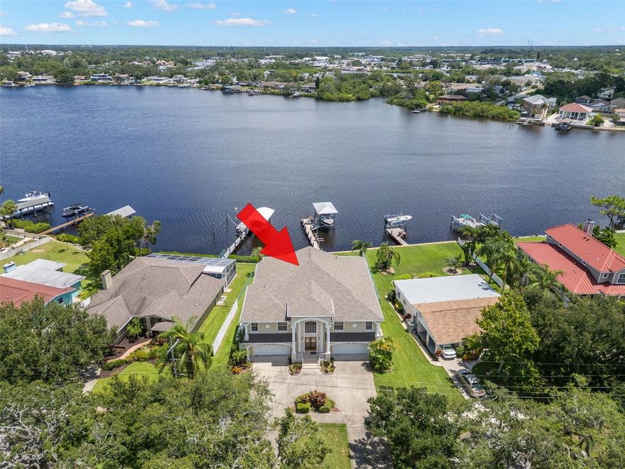 This impressive property features two separate living spaces (upstairs and down), a circular drive, two 2-car garages (4 spaces in total) with endless room for cars, toys, and watercraft.  This Luxury Waterfront Estate is in an X500 flood zone with NO flood damage from the 2024 storm!  It is a split plan home wonderful to entertain in with a beautiful outdoor space including 2 large screened lanai's leading out and looking over the Water, Pool, Dock, Boat and Ski Lift.  As a two story home this home is complete with an elevator making it a breeze to bring up the groceries or for guests who may need an alternative to using the stairs.  This home offers the ultimate Florida lifestyle with incredible water views in the desirable community of Tarpon Springs. Step inside the double-door entry to your grand two-story foyer with chandelier, then head downstairs to the versatile ground floor. Expansive bonus/family room with sliding door access to a screened porch overlooking the in-ground pool that includes a lovely hot tub/spa! Enjoy an efficiency kitchen for poolside entertaining - there is a breakfast bar, refrigerator, microwave, sink and dark wood cabinetry. The first-floor bedroom has a walk-in closet, water views, and private porch access. The full bath with step-in shower offers direct pool access. There are two oversized storage closets as well. From the porch, follow your private walkway to the dock, complete with sink, electric, covered 20,000 pound boat lift, and jet ski lift—perfect for launching right into Florida’s waterways. Use the stairs or elevator to your main living level where you can enjoy the elevated living with panoramic views that will take your breath away. The expansive living room offers high-volume ceilings, pocket sliders to the screened porch, ceiling fans, recessed lighting, gas fireplace, and custom built-ins. The large screened lanai is ideal for outdoor dining and relaxing. Your primary suite is accessed via double-door entry. There are amazing water views and private access to the lanai, two oversized walk-in closets and a spa-like en suite with dual vanities, Jacuzzi soaking tub, oversized step-in shower with bench, and a private water closet with linen storage. Your kitchen boasts white cabinetry, granite counters, and decorative tile backsplash. There is a breakfast bar, breakfast nook with stunning water views, and a pantry with pull-out shelving in addition to an oversized pantry closet. The laundry room is separated by a pocket door and offers built-in cabinetry, deep sink, hanging bar, and washer/dryer. The formal dining area has a lovely chandelier and arched architectural details that open to the grand foyer. The two additonal bedrooms are generous in size. One boasts two wall closets while the other has a walk-in closet. The hall bath has a tub/shower combo and there is another linen closet for storage off the hall. Your outdoor paradise includes a screened lanai with water views, in-ground pool with gated fence and your private dock. Located just minutes from downtown Tarpon Springs historic sponge docks, beaches, dining, and entertainment, this property blends luxury living, unmatched storage, and world-class boating access into one stunning package. Schedule your private tour today and start living your best Florida life!