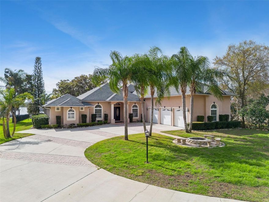 Tucked beneath majestic oak trees and set on nearly an acre of lakefront property, this custom-built estate offers a rare blend of privacy, space, and waterfront living on Lost Lake (also known as Coon Lake), part of the highly sought-after Alligator Chain of Lakes.
Built in 2008, the property includes a beautifully designed main residence and a detached guest apartment, with a total of 5,297 square feet of living space and over 8,100 square feet under roof. The main home features four bedrooms, three and a half bathrooms, and a three-car garage, with thoughtfully designed living spaces and a private 2nd-floor balcony that captures peaceful lake views from multiple vantage points.

Inside, the home balances comfort and function with generous gathering areas, a gas fireplace, a formal dining room with a coffered ceiling, and an updated kitchen completed in 2024 with new granite countertops, backsplash, Z-Tech cooktop, and double ovens with wireless controls. The spacious primary suite offers two large walk-in closets, one of which is constructed as a reinforced safe room, and a spa-style bath with a hydromassage tub, dual vanities, and a separate shower.

Upstairs, the home offers additional flexibility with a large bonus/game room and a private home theater, complete with projector, screen, and sound system, all included with the sale.

A standout feature of the property is the detached guest residence, located above a second three-car garage. This approximately 1,200-square-foot apartment includes a full kitchen, living room, dining area, oversized bedroom (with potential to convert to two bedrooms), and a full bathroom, along with a convenient half bath on the garage level. It provides an ideal space for extended family, guests, rental, or private workspace.

Outdoor living is equally impressive. The expansive lanai and patio areas offer approximately 1,500 square feet of covered and open space,
creating the perfect setting for relaxing or entertaining while enjoying tranquil lake views. The backyard also features a custom koi pond with waterfall and approximately 30 koi fish valued between $10,000 and $15,000, adding a unique and peaceful element to the landscape.

For boating and water enthusiasts, the property includes a private dock with a boat lift and new lift motor, providing direct access to the Alligator Chain of Lakes for fishing, boating, and recreation.

Major updates include a new roof in 2024, a new main HVAC system in 2024, a second Carrier Infiniti HVAC system, approximately six years old, and updated drain lines.

With two separate three-car garages, no HOA, mature landscaping, fruit trees, and nearly an acre of lakefront land, this property offers a rare opportunity to enjoy expansive waterfront living while remaining conveniently close to Harmony, Melbourne, St. Cloud/Lake Nona regions.