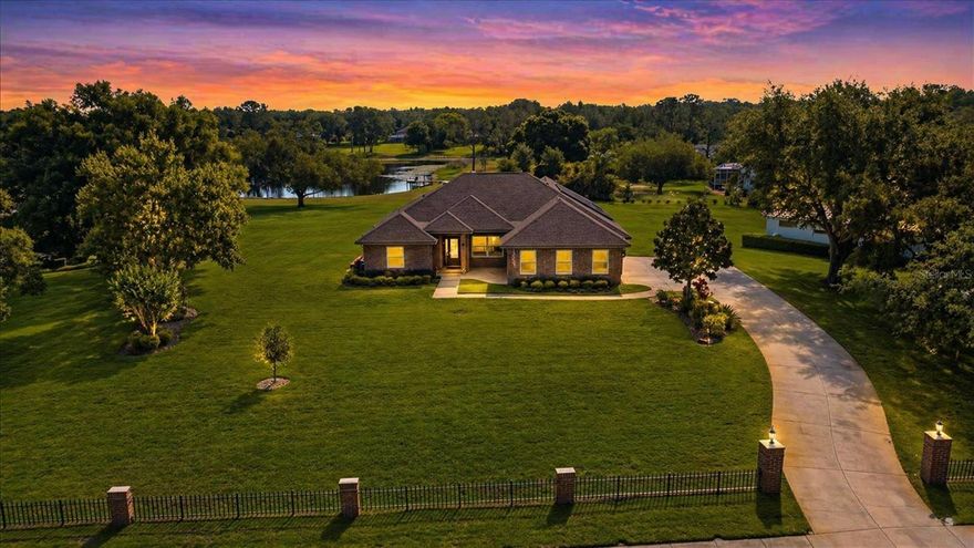 Welcome to this stunning estate in the highly sought-after Lakes of Keystone area in Odessa, offering 1.25 acres of beautifully maintained land with picturesque pond views & access. From the moment you arrive, the home’s impressive curb appeal sets the tone, featuring a stately brick exterior, brick pillar entry, and fenced frontage, all framed by lush landscaping and mature trees. Inside, you are welcomed by elegant formal living and dining spaces with rich hardwood flooring and French doors that open to the pool and patio, creating a seamless indoor-outdoor connection. This thoughtfully designed 4-bedroom, 4-bath home offers a desirable three-way split floor plan, with the primary suite privately situated on its own wing. The spacious primary retreat features crown molding, direct access to the pool, and a luxurious ensuite bath complete with dual granite vanities, soaking tub, separate shower, water closet, and and large walk-in closet. At the heart of the home, the kitchen and living areas showcase soaring vaulted ceilings and beautiful travertine flooring with beveled edges. The kitchen is well-appointed with wood cabinetry, granite countertops, a large center island, Thermador double ovens, Thermador electric cooktop, and a Samsung refrigerator, along with a hidden walk-in pantry and ample storage. The adjacent breakfast nook is a standout feature, highlighted by a charming brick accent wall and three large windows that flood the space with natural light while offering serene views of the pool and backyard. Two secondary bedrooms are located off the main living area—one with a walk-in closet and the other with a built-in—sharing a well-appointed bathroom. Toward the rear of the home, an additional bedroom and full bath serve as a convenient pool bath. Upstairs, a versatile bonus room with a closet and full bathroom provides flexibility as a fifth bedroom, guest suite, or media room. Additional highlights include a well-equipped laundry room with cabinetry and utility sink and a 3-car garage with extensive storage. Hurricane-impact windows installed in 2022 enhance safety and energy efficiency while allowing natural light to pour in throughout the home. Energy-efficient solar panels installed in 2024 help keep the electric bill at an average of $50/month or less (April 2026 invoice $13.85). The property also features a new roof (2024), well pump (2024), water heater (2025) and septic tank pumped (2024). Step outside to your private outdoor oasis, where a screened-in pool, covered lanai, and travertine decking create the perfect setting for entertaining or relaxing, all overlooking the expansive backyard and tranquil pond. Ideally located just minutes from the Veterans Expressway for easy access to Tampa, and zoned for top-rated schools including Steinbrenner High School. This exceptional property offers the perfect blend of space, privacy, and convenience— truly a rare opportunity in Odessa.