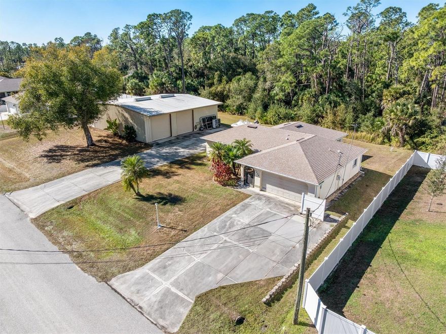 ATTENTION ALL CAR ENTHUSIASTS! This rare property delivers space, style, and serious storage on two generous lots. The showstopper is a massive 50x60 metal pre-fab building designed to hold 6–8 vehicles with ease, plus room for a boat, RV, workshop, or all three. Solid construction and triple wide concrete driveways make parking, storing, and working simple and stress-free. This is a hard-to-find setup that adds huge value and flexibility. The main home offers 3-bedroom, 2-bath split plan with a 2-car garage and beautiful curb appeal. Mature palms, manicured shrubs, and colorful accent rock frame the home and create a polished look. A new roof in 2023, New Hot water heater in 2026 and a new A/C system provide peace of mind and energy efficiency. Inside, the layout is bright and open. The living room features cathedral ceilings, and two large windows that fill the space with natural light.  The main living room/dining room & bedrooms are in need of flooring. The kitchen connects seamlessly to the living and dining areas and includes white raised cabinetry, a pantry closet, stainless double sink, and a breakfast bar ideal for casual meals or entertaining. Just off the dining area is a standout bonus room: a 493-square-foot air-conditioned room with rubber mat flooring. This flexible space works beautifully for fitness, yoga, hobbies, creative projects, or a game room. Sliding doors lead from the back family room to a concrete patio, perfect for grilling or relaxing outdoors. The backyard is quiet and peaceful, backed by a wooded view that adds privacy and charm. The primary bedroom includes crown molding, a ceiling fan, and a spacious walk-in closet. The private bath offers a walk-in tiled shower, large vanity with porcelain sink, new commode and extra storage. Two additional bedrooms feature ceiling fans, with a nearby guest bath offering a tub/shower combo, a new vanity and a new commode. Ceramic tile finishes the kitchen, baths, and entry for easy maintenance. Extra features include hurricane shutters, a water softener with aerator, and exceptional parking options. The home has a double concrete driveway, while the storage building boasts a triple-wide driveway plus additional concrete parking areas. Located minutes from shopping, schools, I-75, Wellen Park, the Atlanta Braves Stadium, Town Center Mall, and the new SMH hospital, this property combines convenience with unmatched space. Opportunities like this do not come around often—schedule a private showing today.