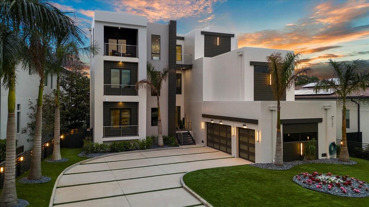 Architectural icon poised on the waterfront in one of South Tampa’s most coveted enclaves, this modern estate embodies luxury, sophistication, and innovation. Featuring six bedrooms, a private office, six bathrooms, and breathtaking water views, this 7,250-square-foot residence offers exceptional amenities, including a home theater, sauna, gym, elevator, pool + jacuzzi, and an oversized 3-car garage—designed for an elevated lifestyle in the exclusive Beach Park neighborhood. A bold sense of arrival begins with the fully enclosed steel gate system, blending security and sophistication. Enhanced by MyQ technology, this gate provides owners control via smartphone, including video surveillance, guest access, and remote functionality. The gourmet kitchen, custom-designed by Allikristé, is a culinary dream with Wolf appliances, dual refrigerators and freezer towers, reverse osmosis filtration with chiller, and a spacious pantry. The open-concept living and dining areas flow effortlessly, featuring RH chandeliers, soaring ceilings, glass walls framing the water, and a sleek gas-powered marble fireplace. A climate-controlled wine cellar with capacity for over 200 bottles ensures your finest vintages are stored. The owners’ suite, offering spectacular sunset views, serves as a luxury retreat. The expansive bedroom includes a private balcony, automated blackout shades, and striking custom wall features. A bespoke built-in wet bar and gas fireplace add both elegance and comfort. The walk-in closet is fully customized, and the oversized bathroom features a walk-in shower, sculptural tub, and double vanities, creating a serene spa-like atmosphere. Each of the five secondary bedrooms is a private retreat, with California Closets, spa-inspired bathrooms, and luxurious finishes. The state-of-the-art media room features Dolby Atmos technology, while the private home gym with a hot rock sauna offers a perfect space for relaxation. Outdoor enhancements include a custom digital-coded secure delivery mailbox, ideal for packages, offering front & rear secure access. The driveway and surrounding landscaping are wrapped in 360-degree artificial turf, minimizing maintenance while providing year-round greenery. A smart underground irrigation system supports live plants, blending nature with modern design. The oversized 3-car garage offers ample space for vehicles and storage, plus an EV charger. The home is integrated with a Savant smart home system, allowing seamless control of lighting, audio, climate, and automated blinds, all compatible with Apple HomeKit. Designed for entertaining, the outdoor spaces rival any five-star resort. A custom saltwater pool and spa with dual pumps, new gas heaters, fire features, and AquaLink smart controls set the tone for relaxation. The adjacent designer summer kitchen, equipped with a 40” grill, sink, and refrigerator, invites al fresco dining, while the rooftop terrace offers panoramic water views. A unique fire feature with direct access to a wet bar creates a show-stopping setting for sunset gatherings. The private boat dock with an automatic lift accommodates two jet skis and can be retrofitted for vessels up to 6,000 lbs, providing effortless access to open water year-round. Powered by a Generac 26 kW generator, this estate ensures reliable power during any interruptions. This residence is more than a home. It’s where sophistication meets sanctuary.