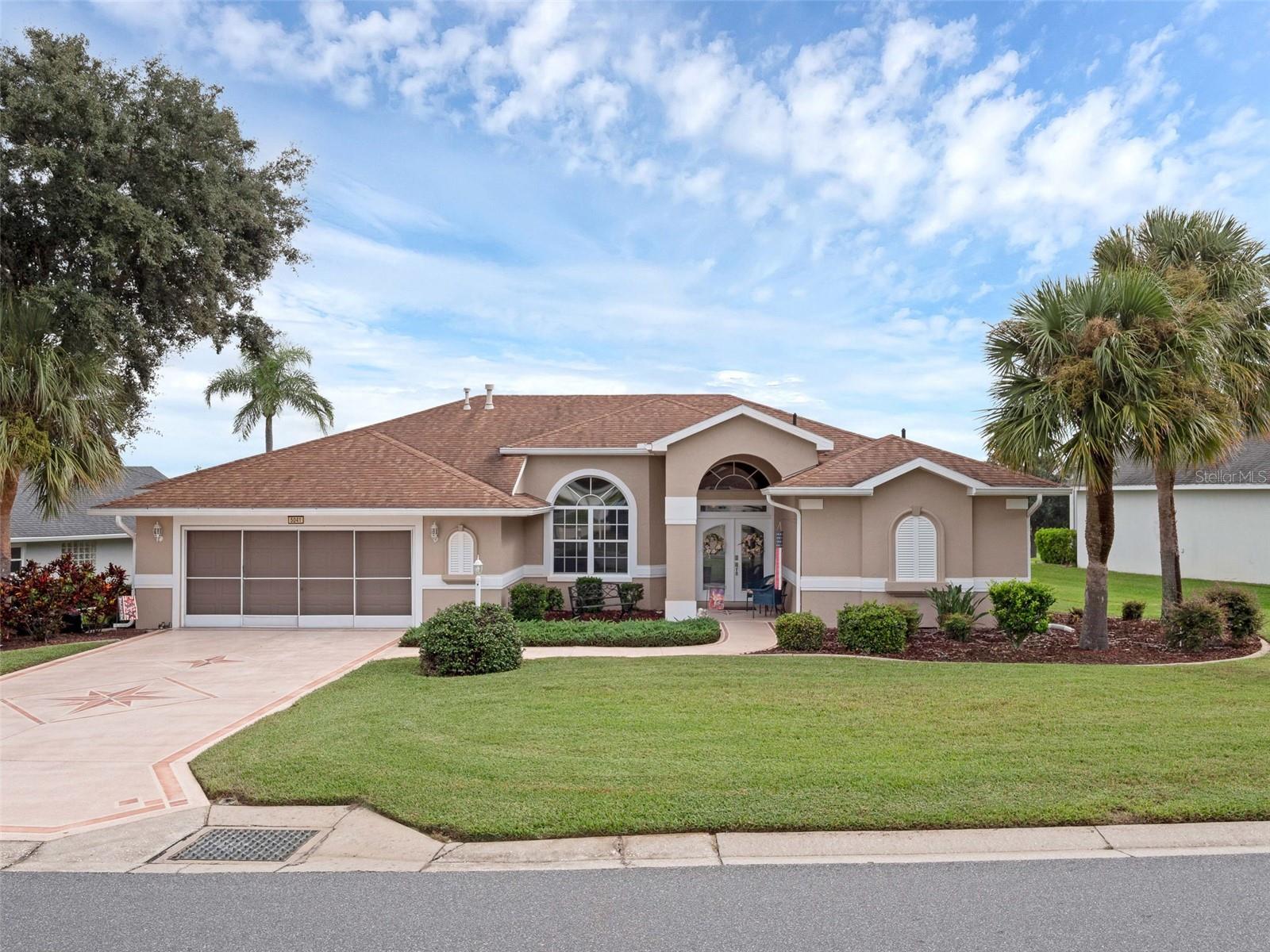 Welcome to your sun-drenched sanctuary in the heart of Royal Highlands—a sophisticated Scarborough Model where elegance meets comfort. Spanning an expansive 2,214 square feet, this residence is designed to celebrate the Florida lifestyle, with abundant natural light that accentuates every detail and creates a welcoming ambiance from dawn till dusk. Perfectly perched on a premium lot, this home commands sweeping views of the Monarch Golf Course’s picturesque 1st hole. Within walking distance to the Crown & Shield Restaurant & pro shop, driving range, and the Great Hall. Royal Highlands is a gated 55+ golf community where residents enjoy private roads, sparkling lakes for fishing, sidewalks winding through scenic pastureland, and everyday encounters with Florida wildlife. With nearly 50 clubs and activities, there’s always something new to explore and friendships to be made. As you step inside, your gaze is drawn straight through the open spaces, out the back sliding doors, and onto the lush green course. High ceilings soar overhead, an abundance of windows invite sunlight to dance across every room. The wide-open floor plan offers versatility and comfort, perfect for entertaining guests or relaxing. The enclosed L-shaped Florida Room is a haven for relaxation or social gatherings, bathed in natural light and offering panoramic views of the golf course. Step out onto the bird-caged screen lanai, where you can sip your morning coffee. Culinary enthusiasts will fall in love with the kitchen, which boasts gleaming stainless-steel appliances and thoughtfully designed pull-out cabinets for easy access and storage. Solid surface countertops provide both beauty and durability, while the central island offers additional workspace for meal prep. A spacious walk-in pantry ensures you have room for all your ingredients and kitchen gadgets. Enjoy casual dining in the breakfast nook, which overlooks the sunny Florida Room, making every meal a delightful occasion. Offering three generously sized bedrooms, each with ample closet space. This home ensures every guest feels welcome and comfortable. The owner’s suite is a true retreat, featuring a garden tub for relaxing soaks, a walk-in closet & Roman shower, comfort-height dual vanities, and a private comfort-height commode. An oversized garage with room for your golf cart means convenience is always at hand. The attic offers additional storage space for your seasonal items, while a dedicated workbench is perfect for projects and hobbies. The separate laundry room, streamlines daily chores, keeping life organized. The property is fully irrigated, ensuring lush, healthy landscaping year-round and adding to the home’s curb appeal. The water heater was replaced in 2024, the roof was updated in 2017, and the HVAC system was installed in 2019. Additionally, the home is protected by a transferable termite bond. Royal Highlands stands out for its exceptional amenities covered by a low monthly HOA fee, which includes cable and high-speed internet. Residents enjoy access to two sparkling pools, a state-of-the-art fitness center, courts for tennis and pickleball, craft rooms for creative pursuits, a well-stocked library, and softball fields for friendly competition. The community’s lakes invite fishing enthusiasts, while miles of sidewalks encourage leisurely strolls through nature. You’re just minutes from South Lake Hospital, shopping centers, MCO, amusement parks, historic areas, and The Villages.