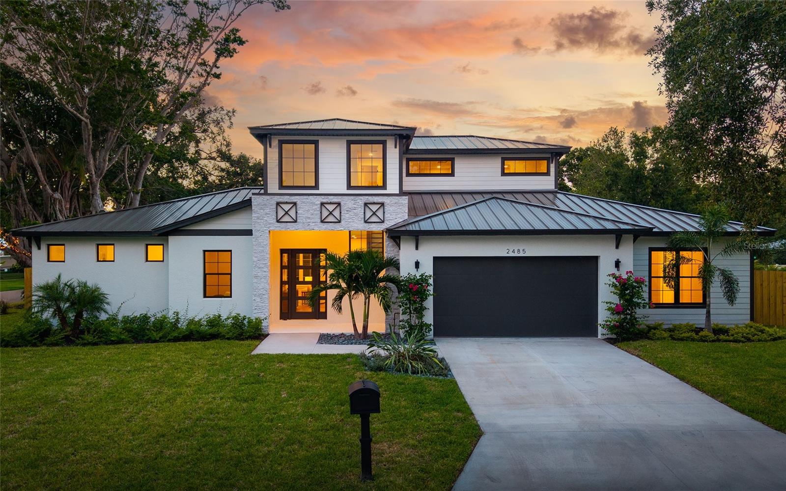 Contemporary residence in Paver Park just east of downtown Sarasota. Wow, what a great location! Close to everything that makes Sarasota such a great place to live — across from the Legacy Trail, within one mile of Payne Park, downtown and Publix, and just one-and-a-half miles to Bayfront Park, Sarasota Memorial Hospital and Southside Village. This 2,876-square-foot residence (4,197 total under roof) provides top-quality construction including concrete block first-floor exterior, standing-seam metal roof, and impact-rated windows and doors — all set on Zone X high elevation. Inside, refined selections include white oak wood floors, solid-wood cabinets with dovetail joinery and soft-close doors, quartz countertops with waterfall edges in kitchen, solid-core interior doors, Moen mixed metal fixtures and Bosch appliance package with induction cooktop. The layout includes four bedrooms, a loft, three full baths, a powder room, office, dramatic two-story foyer, and a serene owner’s suite with sliding glass doors to a private lanai, walk-in closet and en-suite bath. The open-concept great room, dining area and chef’s kitchen spill out to a covered lanai with an outdoor kitchen, creating seamless indoor-outdoor living around the private pool. Additional highlights include a custom TV/fireplace wall with 60-inch multi-color flame electric fireplace flanked by built-in white oak storage cabinets and upgraded landscape package with mature trees. Classic, yet timeless. Thoroughly today. A home for loving your Sarasota lifestyle.