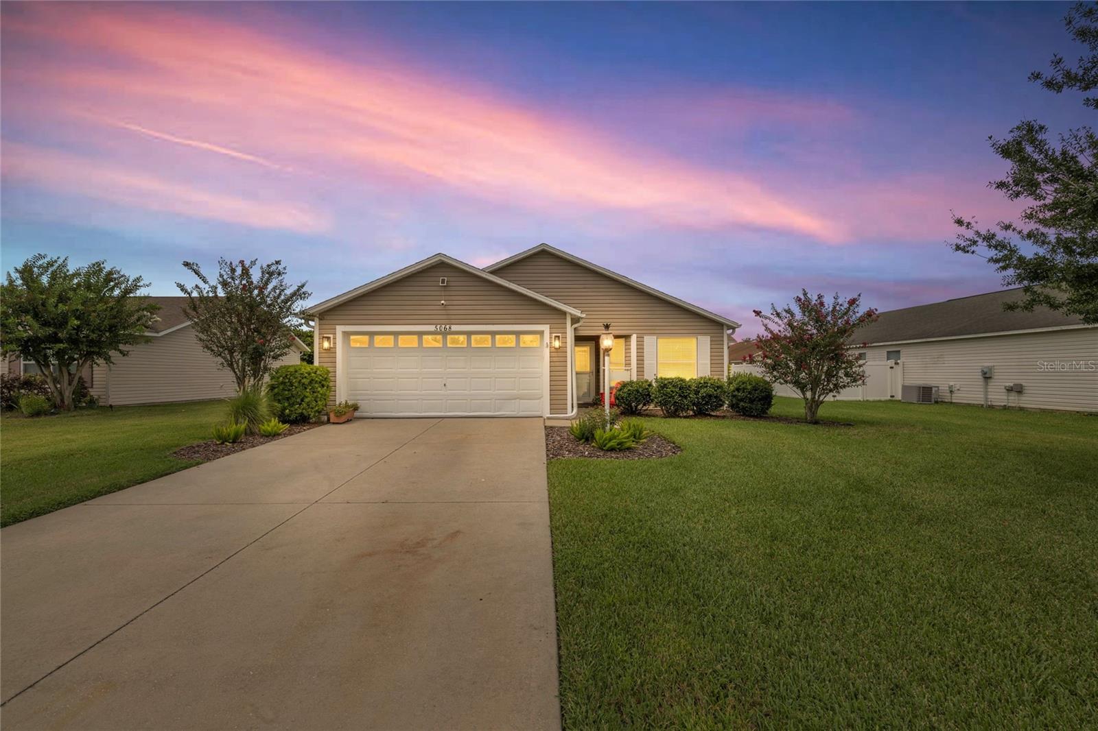 Prime Location Near The Villages Charter School! Easy golf cart assessable to all The Villages offers. Welcome to this beautifully maintained 3-bedroom, 2-bath At Ease model home, complete with a 2-car garage, located in the highly sought-after family-friendly neighborhood of Bison Valley. Just under a mile from The Villages Charter School and close to CR 466, providing easy access to the area’s most popular restaurants, shops, and essential services. This home offers the perfect blend of comfort, convenience, and lifestyle. Step inside and immediately feel at home with luxury vinyl plank flooring throughout—no carpet, fresh paint, and soaring ceilings that create a bright, airy atmosphere. The spacious open-concept layout is perfect for both everyday living and entertaining. The kitchen is a standout feature with light cabinetry, a stylish backsplash, new light fixtures, stainless steel appliances, and a large farmhouse-style sink. The indoor laundry room offers plenty of space and storage. The guest bathroom is smartly placed near the guest bedroom, providing privacy and functionality. The master suite is a true retreat, featuring vaulted ceilings, a lighted ceiling fan, a spacious walk-in closet, and an ensuite bath with dual sinks and ample counter space. Step out through the sliding glass doors onto a screened lanai, ideal for morning coffee or relaxing evenings. Just beyond is a concrete patio slab, perfect for grilling and outdoor gatherings. The lush backyard and blooming crepe myrtle tree out front add charm and curb appeal.
Live minutes from shopping, dining, and entertainment near CR 466 and at Lake Sumter Landing. Whether you’re raising a family or looking for a peaceful neighborhood with easy access to The Villages, this home checks all the boxes!