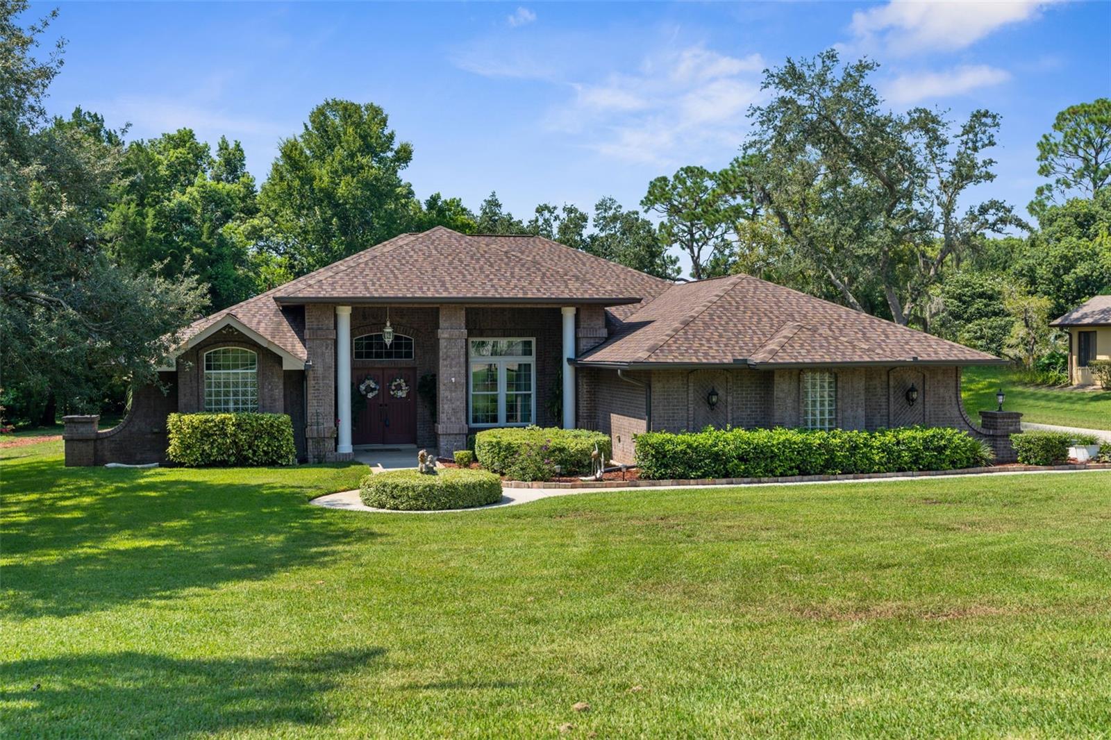 One or more photo(s) has been virtually staged. WELCOME TO YOUR PRIVATE FLORIDA OASIS! This beautifully maintained POOL home offers an OPEN-CONCEPT, SPLIT FLOOR PLAN with incredible upgrades, spacious indoor and outdoor living, and PEACEFUL PRIVACY with no rear neighbors!! From the moment you enter, you’re greeted by a large foyer and coat closet that opens into the formal living room and dining area—perfect for welcoming guests or hosting gatherings. The heart of the home is the EXPANSIVE, OPEN KITCHEN, thoughtfully designed with STUNNING GRANITE COUNTERTOPS, UPGRADED APPLIANCES, and a LARGE CENTER ISLAND! The family room features a COZY FIREPLACE, BUILT-IN SURROUND SOUND, and MARBLE-LOOK CERAMIC TILE FLOORING that runs throughout all of the main living areas. A WHOLE-HOUSE SPEAKER SYSTEM extends throughout the home, lanai, and garage, elevating your entertainment experience. The PRIVATE PRIMARY SUITE is located at the front of the home and features POOL ACCESS, DUAL WALK-IN CLOSETS, and a LUXURIOUS EN SUITE BATH with an OVERSIZED JACUZZI TUB, WALK-IN SHOWER, DUAL VANITIES, and a PRIVATE WATER CLOSET. On the opposite side of the home, an additional bedroom is a SOLID CONCRETE HURRICANE ROOM with an EXTERIOR DOOR, designed for safety and versatility. The hall has a full bath that also offers POOL ACCESS—ideal for guests. A THIRD full bath, located near the laundry room, includes a STEP-IN SHOWER, VANITY, AND TOILET. The SPACIOUS GARAGE includes a UTILITY SINK, TOOL AREA, and convenient access to the INDOOR LAUNDRY ROOM complete with WASHER, DRYER, AND A SECOND SINK. Step outside to a SCREENED-IN POOL DECK, featuring a HEATED POOL AND JACUZZI (3000 BTU HEATER), a LARGE COVERED AREA FOR OUTDOOR FURNITURE, and a PRIVATE BACKYARD that’s still generous in size despite the pool. The FRONT YARD is equally impressive—OVERSIZED AND WELL-MANICURED for excellent curb appeal! This home is loaded with upgrades: HURRICANE-IMPACT WINDOWS (2019) with a TRANSFERABLE LIFETIME WARRANTY, ROOF (2019), and an A/C SYSTEM (11 YEARS OLD) that is SERVED TWICE A YEAR. Flooring includes PORCELAIN TILE THROUGHOUT THE MAIN AREAS and CARPET IN THE BEDROOMS. Bathrooms have WALK-IN SHOWERS and a GARDEN JET TUB in the primary bathroom. Additional features include a WHOLE-HOUSE WATER SOFTENER, a WATER FILTRATION SYSTEM, a NEW WELL PUMP FOR THE SPRINKLER SYSTEM, 6-INCH GUTTERS, and a 5-YEAR TRANSFERABLE PAVER SEALER WARRANTY. Utility bills are economical with SEPTIC + CITY WATER (WATER BILL ~$18/MO) and AVERAGE ELECTRIC $190–$210/MO. CURRENT HOMEOWNER’S INSURANCE IS APPROX. $1,700/YEAR. THIS IS A RARE OPPORTUNITY TO OWN A MOVE-IN READY HOME WITH LUXURY FEATURES, PRIVACY, AND PEACE OF MIND. Schedule your private tour today!