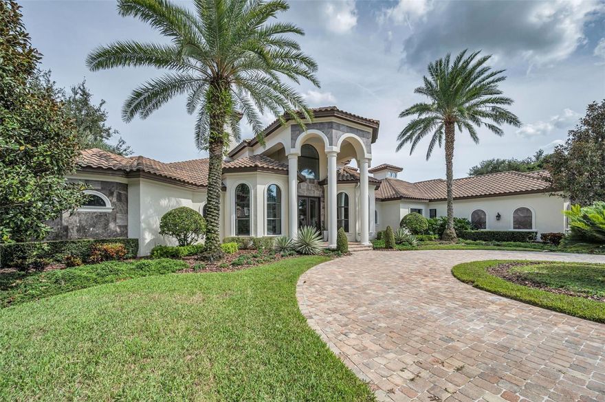 Located in the prestigious gated community of Florencia at the Champion’s Club in Trinity FL, this one-of-a-kind custom estate is set on one of the largest and most desirable lots, offering panoramic views of the lake and the 2nd hole of the renowned Fox Hollow Golf Club. Boasting 5,965 SF of living space and 9,100 total SF, this exquisite residence offers 6 bedrooms and 7 full bathrooms, including a separate 1 bedroom, 1 bath guesthouse. Designed for luxury living and grand entertaining, the home welcomes you with soaring 26-foot ceilings, a dramatic circular staircase, and stunning views of the golf course, water, and resort-style outdoor living area. The expansive layout features a three-way split floor plan, providing exceptional privacy throughout. The oversized primary suite is a private retreat with direct pool access, dual walk-in closets, a double-sided walk-in shower, and a centerpiece soaking tub. The gourmet kitchen is a chef’s dream, featuring high-end appliances, custom cabinetry, designer backsplash, and a large central island that opens seamlessly to the family room and game room, all with unobstructed views of the outdoor oasis. The outdoor living space is truly exceptional, highlighted by a sparkling pool with a large spill-over spa, a fully equipped summer kitchen, cozy fireplace, three distinct lounge areas, and a dining space perfect for entertaining. The detached guest casita is located just off the pool and outdoor kitchen, ideal for visitors or extended family. Additional features include a private office with custom built-ins, bonus/media room, exercise room, and a dedicated study or flex area. A circular paver driveway and lush landscaping complete the impressive curb appeal. This luxury community offers convenient access to top-rated schools, shopping, dining, hospitals, nearby beaches, and the Suncoast Parkway, and just 30 minutes from Tampa International Airport. Residents enjoy exclusive access to Champion’s Club amenities, including a resort-style pool and spa, clubhouse with catering kitchen, tennis and basketball courts, fitness center, and a calendar of resident-only events. This custom-built masterpiece offers an unmatched blend of luxury, privacy, and lifestyle in a secure, amenity-rich setting. Schedule your showing today.