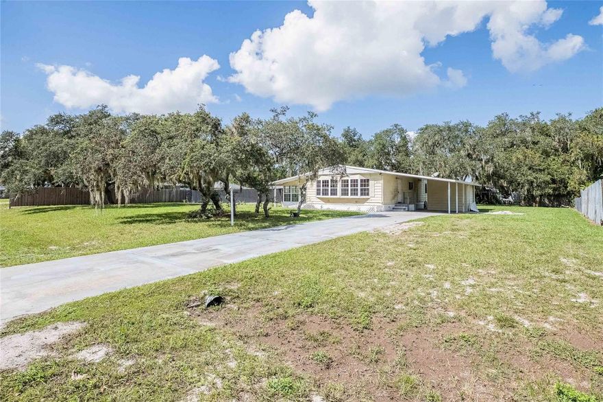 Welcome home! This 3 bedroom, 2 bathroom manufactured home sits on just under half an acre of fully fenced land, offering plenty of room for the family, friends, pets, and outdoor fun. With no HOA and no lot fees, the land is truly yours to enjoy and make your own; add a garden, play area, or workshop, the possibilities are endless!  Inside, you’ll find a spacious kitchen that flows easily into the dining area and living room, perfect for family gatherings or entertaining friends. The primary bedroom includes a generous walk-in closet, while the indoor laundry room adds everyday convenience. Outside, there’s carport parking and a long driveway providing ample space for multiple vehicles.  This home is ideal for a savvy buyer ready to bring it back to life, whether you’re looking for your own affordable slice of Florida living or an investment property with great potential.
