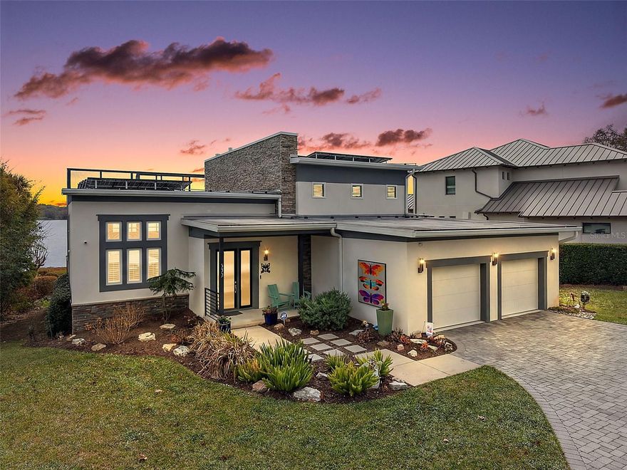Indulge in the rare privilege of true lakefront luxury on the coveted shores of Lake Gertrude—where refined architecture, cutting-edge efficiency, and breathtaking panoramas converge in one extraordinary custom estate. Designed for the discerning buyer, this contemporary masterpiece showcases an innovative open-concept design framed by disappearing walls of glass that effortlessly blend indoor and outdoor living. The expansive screened terrace—complete with a summer kitchen, tongue-and-groove ceiling, and statement chandelier—becomes a private waterfront lounge suspended above shimmering waters. Host unforgettable evenings beneath painted sunsets and starlit skies as boats glide quietly across the lake. Inside, polished concrete floors, soaring ceilings, and a dramatic stacked-stone feature wall create a striking yet sophisticated ambiance. A sleek gas fireplace anchors the grand living space, while the chef’s kitchen rivals those found in luxury design magazines—Quartz surfaces, custom European-style cabinetry, premium stainless appliances, an oversized waterfall island, and a JennAir gas range deliver both beauty and performance. The main-level owner’s retreat is a sanctuary of tranquility and refinement. Wake each morning to uninterrupted lake views from your private sitting area. The spa-caliber bath exudes understated opulence with Quartz vanities, dual sinks, porcelain tile, and a frameless glass shower designed for indulgent relaxation. Upstairs, two private guest suites—each with its own en-suite bath and walk-in closet—offer elevated comfort. One features a secluded balcony overlooking the water, an intimate vantage point for sunrise reflections across the lake. This residence also embraces modern sustainability with solar power, ensuring exceptional efficiency without compromising luxury. Beyond the interiors, manicured grounds roll gently to a reinforced aluminum seawall and private dock—your gateway to boating and water skiing on the pristine waters of Lake Gertrude. Moments from the boutiques, fine dining, and cultural charm of downtown Mount Dora, yet worlds away in privacy and prestige, this is more than a home—it is a statement. For those who expect nothing less than exceptional, welcome to your private lakeside legacy.
