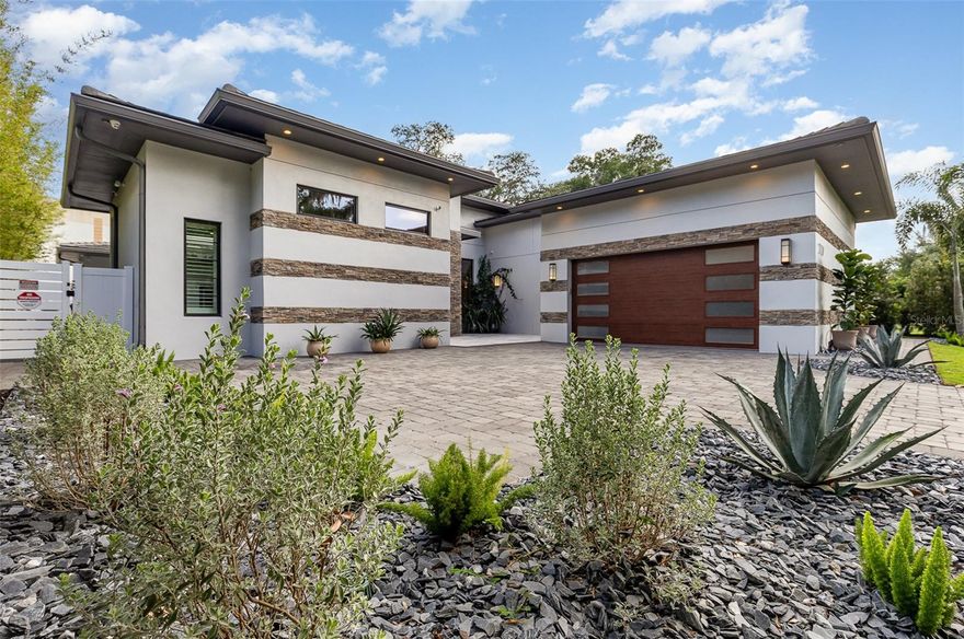 Welcome to a one-story custom-built contemporary home in Winter Park, completed in 2019 with new landscaping recently added. This stunning property offers 5 bedrooms, 4 full bathrooms, and one powder room in a split-floor plan with luxury finishes throughout. Upon entry, a grand foyer with soaring ceilings and exquisite lighting sets the tone for sophistication in the entire home. The formal dining room, adorned with designer fixtures and custom flooring, provides an elegant space for gatherings. A pass-through bar, featuring beautiful display shelves, connects the dining room to the great room, adding both convenience and style. The kitchen features top-of-the-line appliances, including a gas cooktop, ample cabinets, quartz countertops, an island, and a hidden walk-in pantry. The great room, with its stunning architecture and abundant natural light, features a gas fireplace and opens up to a tranquil outdoor space overlooking a heated pool and spa. This serene oasis is accessible through 10-foot sliding doors that seamlessly create a smooth transition for indoor and outdoor entertaining. The spacious primary suite, with a view of the pool area, creates a peaceful retreat. It includes a generous walk-in closet upon entry, a dedicated coffee bar nook, and a double-sided gas fireplace linking the bedroom with the luxurious bathroom that serves as a tranquil sanctuary, boasting double sinks, a lavish walk-in shower equipped with body jets, and a distinct vanity section. Each of the three additional bedrooms offers private en-suite bathrooms. The guest suite has direct access to the pool area for convenience. The fifth bedroom is a versatile space that can serve as a bedroom, office, or nursery, conveniently located near the master suite. Highly acclaimed Winter Park schools, proximity to local hospitals, Interlachen Country Club, Winter Park Racquet Club, walking distance to YMCA, Phelps Park, and minutes from shopping and dining on Park Ave make the location of this home very desirable! With numerous exceptional features, this home invites you to experience its luxurious beauty firsthand.