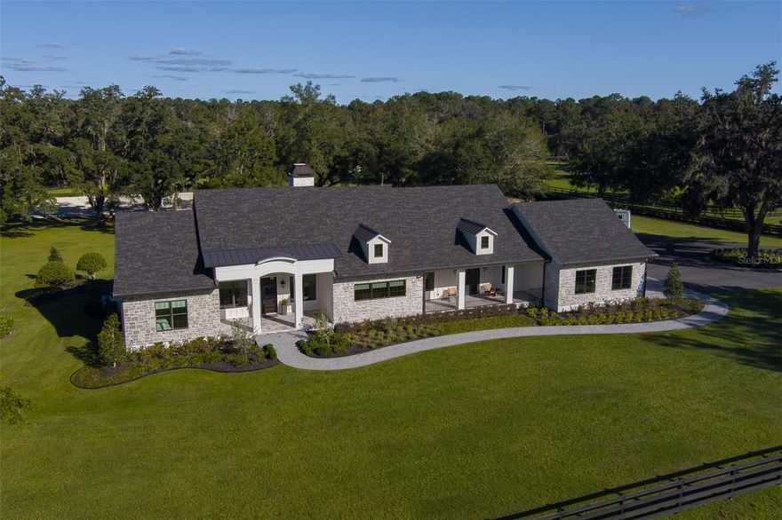 Fall in love with this stunning three bedroom, three and-one-half bath, custom 2022 home on 10 acres dotted with majestic live oaks. The home features 5,500 square feet under roof spread across a single story that includes an open-plan design, study and large outdoor lanai and living space. The property features abundant natural light, beautiful views from every room and professionally designed interiors. The property is located in coveted 225A Golden Corridor, and only 3 miles door to door from the World Equestrian Center. Tucked off the road and accessed through custom gates with limestone pillars and an asphalt driveway, this low-maintenance home is clad in Hardie Artisan siding topped by a blend of synthetic shake roofing and standing seam metal. The entry porch is graced with an oversized mahogany door. This home appears to float above the pastures and has a direct line of sight to an irrigated 100 X 200 ft arena flanked by 4 centurion oak trees. 14 ft tray ceilings with Northwestern spruce box beams and 18ft sliding glass doors add volume and brighten the primary living space with natural light. French oak flooring add a casual, yet upscale touch throughout. The Great Room features a double sided fireplace and direct access to the outdoor lanai. The kitchen is dressed in neutral tones with Calacutta gold marble countertops and anchored by a darker-hued central island with counter seating. Appliances by Wolf and SubZero include a 6-burner range with double oven, two refrigerators. French doors open to a grill porch with built-in gas grill. The adjacent dining room is surrounded by windows overlooking the heated saltwater pool and spa, perfect for entertaining and alfresco dining. Located just off the Great Room, the cozy study has its own private patio with stained cypress plank ceiling and surrounding landscape. The primary suite offers extensive views of the back of the property. The primary bath offers a soaking tub, walk-in shower, and a symmetrical pair of vanities clad in Oyster Grey marble. Two ensuite guest rooms are located on the opposite side of the home. Additional features of this home include automated shades, landscape lighting on all live oaks. A whole home and property generator for safety and peace-of-mind, along with a 500 gallon in ground propane tank. The farm is complete with a professionally installed, irrigated, all weather riding arena, 3 oversized pastures with 4 board fencing with no climb around the property perimeter and a 26 X 16 run-in shed with rubber Mats. Barn pad with access to electric is already in place for your dream barn to be built, exactly as you wish, plans are included and can be revised per buyers request.