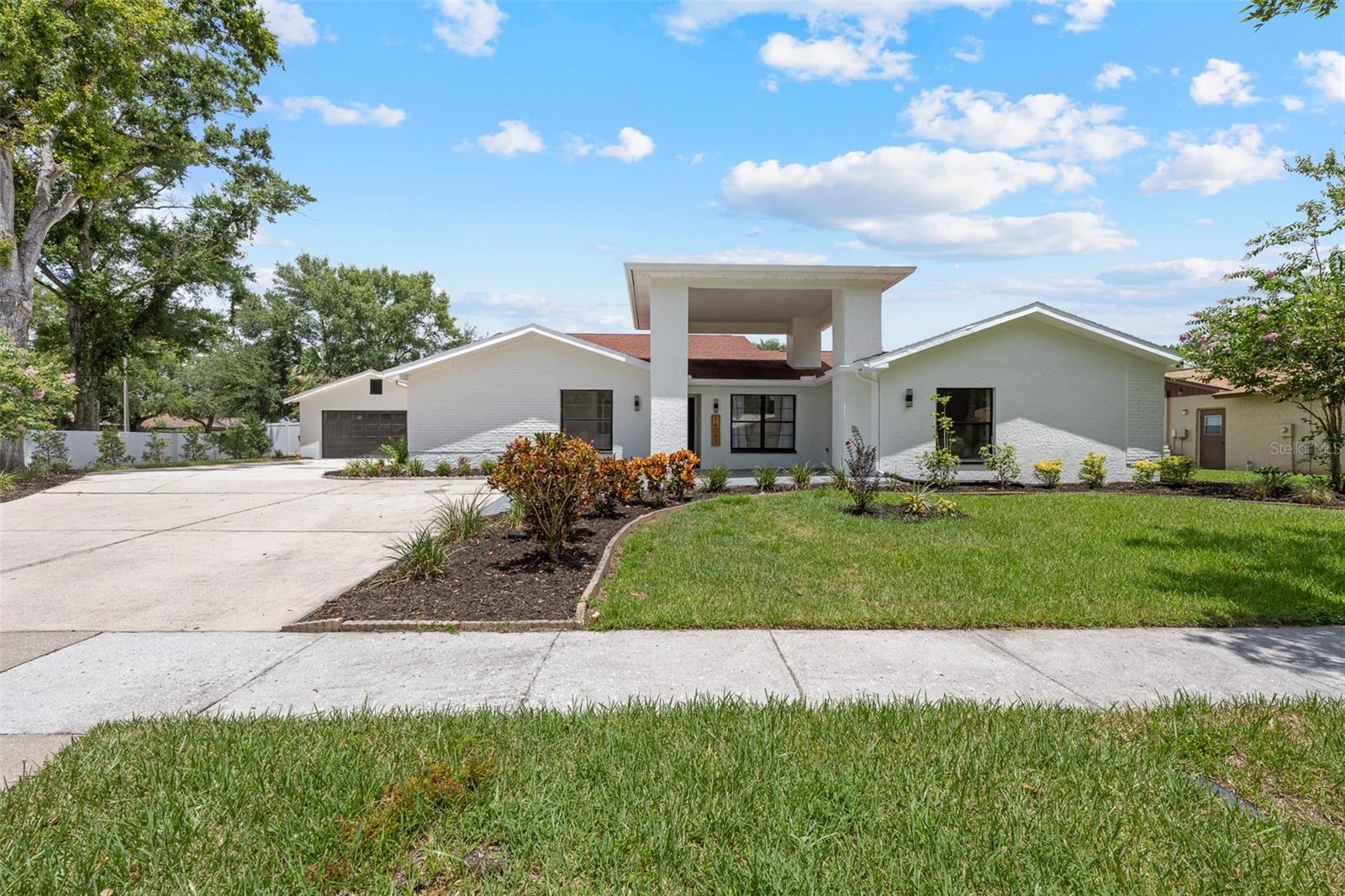 Welcome to this beautifully updated home in the highly sought-after Carrollwood Village community of Tampa. Situated on a large corner lot with an expansive driveway and two-car garage, this property offers impressive curb appeal and functionality. Step through the grand entrance into a spacious, open-concept layout with a split-bedroom floor plan designed for both comfort and privacy. The home features five bedrooms, three and a half bathrooms, and multiple flexible living spaces. The large primary suite includes a walk-in closet and a beautifully updated en-suite bath with a glass-enclosed shower and dual vanity. A secondary bedroom located off the primary is perfect for a nursery or home office. The fifth bedroom is a standout feature, offering private exterior access and endless possibilities—ideal for a guest suite, home office, playroom, media room or in-law suite. Whether you’re accommodating extended family, need a private workspace or looking for a private playroom, this flexible space adapts to your lifestyle. The heart of the home is the modern kitchen, complete with stainless steel appliances, hood vent, quartz countertops and backsplash. Enjoy meals in the formal dining room, relax by the modern fireplace in the family room, or entertain in the formal living room at the front of the home. Multiple sliding doors lead to a screened-in pool and expansive patio—perfect for Florida living. A full pool bath adds convenience, and the oversized laundry room includes cabinetry for storage. Located in a vibrant community with access to parks, playgrounds, tennis and pickleball courts, basketball, walking trails, and the Carrollwood Village Park featuring a dog park, splash pad, skate park, and more. Conveniently located near major grocery stores, restaurants, and entertainment, with quick access to Tampa International Airport, downtown Tampa, and the Gulf beaches—this home truly has it all!