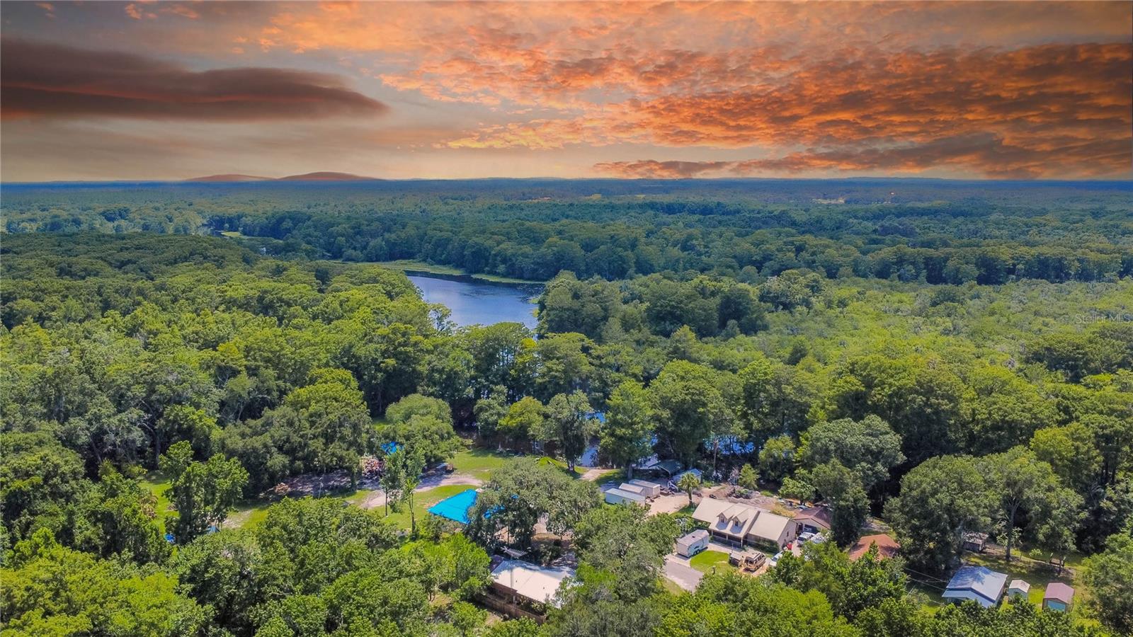 CUTE, COZY & AFFORDABLE! 1997 two-bedroom, one-and-a-half-bath furnished home with 676 OF living area is the perfect retreat. This hidden gem is nestled on a spacious corner parcel with deeded access/boat ramp to the breathtaking Withlacoochee River across the street. Interior features include a galley-style kitchen complete with a pantry, gas range, wood cabinets, tile countertops, stainless steel appliances, and a breakfast bar. The spacious two-car garage includes a washer, dryer, utility sink, and a half bath, along with an attached metal workshop for added functionality. Enjoy river views from the front screened porch or relax at the patio area shaded under the oak tree. Perks include a keyless entry, an 8-camera video system, Simply Safe Wi-Fi security, tile flooring throughout, updated interior and exterior paint, a metal roof (2022), updated AC (2019), and a Wi-Fi-enabled garage door. This affordable home provides easy access to both Sumter and Citrus Counties and to top is off there are NO RESTRICTIONS and it has NEVER FLOODED!