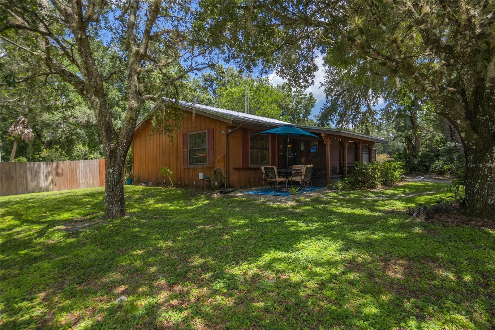 CUTE, COZY & AFFORDABLE! 1997 two-bedroom, one-and-a-half-bath furnished home with 676 OF living area is the perfect retreat. This hidden gem is nestled on a spacious corner parcel with deeded access/boat ramp to the breathtaking Withlacoochee River across the street. Interior features include a galley-style kitchen complete with a pantry, gas range, wood cabinets, tile countertops, stainless steel appliances, and a breakfast bar. The spacious two-car garage includes a washer, dryer, utility sink, and a half bath, along with an attached metal workshop for added functionality. Enjoy river views from the front screened porch or relax at the patio area shaded under the oak tree. Perks include a keyless entry, an 8-camera video system, Simply Safe Wi-Fi security, tile flooring throughout, updated interior and exterior paint, a metal roof (2022), updated AC (2019), and a Wi-Fi-enabled garage door. This affordable home provides easy access to both Sumter and Citrus Counties and to top is off there are NO RESTRICTIONS and it has NEVER FLOODED!