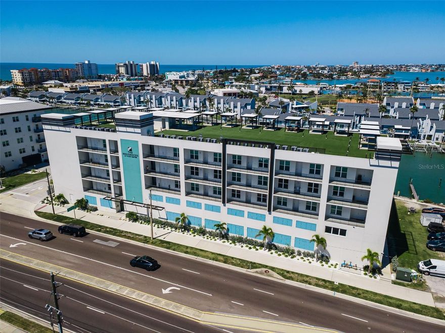 Indulge in Elevated Coastal Luxury in this Like-New, Waterfront End Unit Condo at The Residences at Town Center, an EXCLUSIVE 27-unit waterfront enclave in the HEART of Madeira Beach. Perched on the second-floor corner with expansive Harbor and Intracoastal views, this 3BR, 3BA Coastal contemporary, END UNIT residence offers over 1800 sq ft of refined interior living plus a 28-ft balcony that captures glowing sunsets and gentle waterside breezes.  Also included is a private rooftop cabana (17) with sweeping Bay views, two under-building parking spaces and a dedicated storage room. Inside this LUMINOUS corner residence of distinction, the open-concept design is both elegant and inviting with expanded windows, elevated finishes, and the effortless charm of refined beachside living with soaring 10-ft ceilings all creating a light-filled, sophisticated atmosphere. The designer seaside-luxury Kitchen showcases quartz countertops, solid surface backsplash, solid wood 42-inch custom cabinetry, stainless steel appliances, entertainment sized center island and elegant finishes that amplify everyday living.  Other design-forward interior finishes with refined beachside elegance include porcelain tile plank flooring, impact-rated windows and doors, plantation shutters, electric shades, a large utility room with full sized washer & dryer and a thoughtfully designed split-bedroom layout to include a waterfront Primary Suite with a spa-like bath and walk-in closet that will provide both comfort and privacy along with a sense of quiet exclusivity. This boutique waterfront community built in 2024 offers resort-style amenities including a heated waterfront Inground pool and spa, fitness center, community center / clubhouse with a full kitchen and a spectacular rooftop terrace with 360-degree views stretching from the Gulf beaches to the downtown St. Petersburg skyline. Two assigned, under-building and ample guest parking spaces along with golf cart parking and pet-friendly policies with no size restrictions enhance the effortless lifestyle. Located steps from local dining, boutique shopping, the upcoming Beachmaker Resort by Marriott, and the sugar-soft sands of Madeira Beach, this EXQUISITE residence delivers an unparalleled blend of luxury, convenience, and coastal serenity. With 30-day minimum rentals, it offers exceptional flexibility for full-time living, a seasonal retreat, or investment potential. The Residences at Town Center, where elevated design, tranquil water views, and resort-style amenities come together for an UNMATCHED coastal lifestyle.