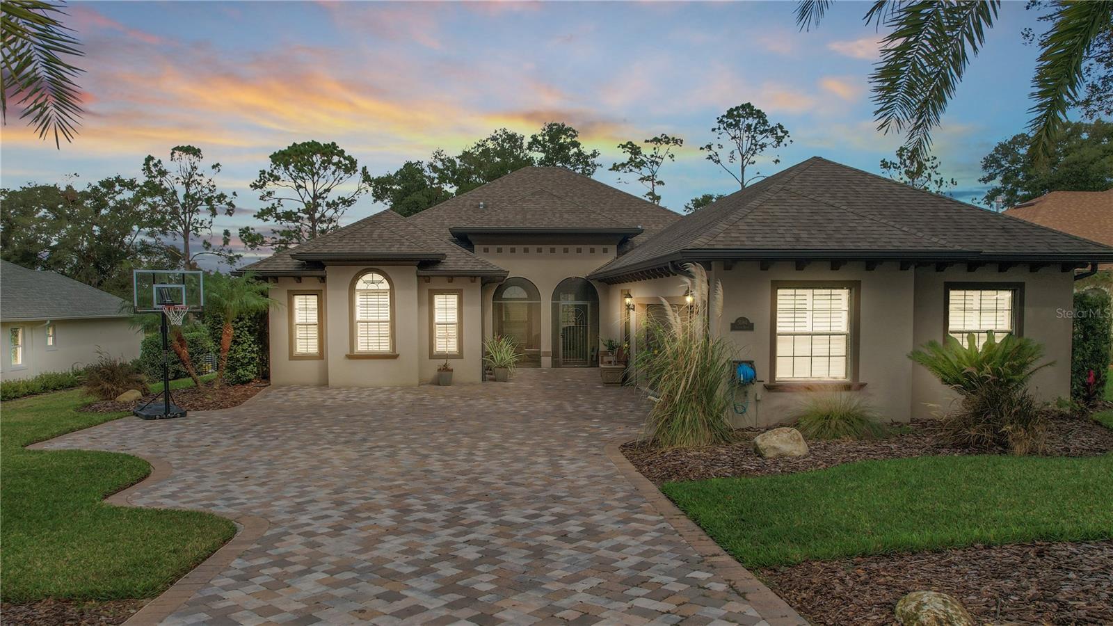 Experience life to the fullest in this 4 bedroom / 3 full bath home in Harbor Hills, a gated golf community nestled on the shores of Lake Griffin on the sought after Harris Chain of Lakes. Your new home has stunning views of the golf course, along with two rustic ponds, seen through sliding glass pocket doors across the back of the great room. Looking out, you see a salt chlorinated pool w/waterfall, a rustic stone horizontal gas fireplace and over 1,000 sq. ft. of covered/screened lanai. The house was built in 2018, however underwent an executive remodel in 2022 including: A true cook’s kitchen featuring Cambria Quartz countertops, an oversized island for bread and pasta making, double KitchenAid convection ovens, GE Profile gas cooktop with high flow vent hood, fully custom pantry and storage closet, and upgraded lighting to set any mood desired. The floors have been upgraded to Wood Plank Porcelain Tile throughout, the lighting elevated from builder grade, all closets are now custom, and the windows are covered with plantation shutters. The Owner's Bedroom features an En Suite w/walk through Roman shower including an added rain head, two vanities and a large soaking tub, as well as two custom built closets. Another added bonus is the whole-house purifier. The remaining three bedrooms are well sized with large upgraded custom closets and two of the bedrooms have en suites.The exterior of the home has been enhanced as well. As you pull into the expanded custom paver driveway with 18-foot sylvestris palms on either side, you will notice that the yard and landscaping accentuate the home's beauty. Podocarpus & Viburnum shrubs surround the home, giving a warm sense of privacy adding to the décor. A lanai garden enclosed by a wrought iron fence has been built on the left side of the home and fruit trees line the back. This one of a kind home is located in Harbor Hills, which is one of the most sought after Exclusive, Gated Golf & Waterfront Communities that is just minutes to The Villages, shopping, restaurants, doctors, medical facilities, grocery stores and more! Call today for your private showing and also be sure to watch the video!