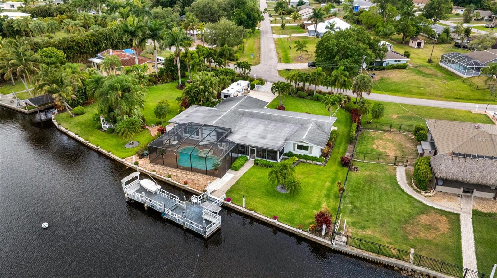 Stunning Riverfront Oasis with Safe Harborage and Expansive Views! Welcome to this beautifully renovated 3-bedroom, 3-bathroom pool and spa home, ideally positioned behind a tranquil oxbow that offers both sweeping open river views and secure harborage for your boats. Featuring a spacious dock, this home is a true waterfront gem. Inside, you'll find a completely updated interior with a brand-new chef’s kitchen outfitted with top-of-the-line appliances, elegant tile flooring throughout, fully remodeled bathrooms, plantation shutters, and impact windows complemented by accordion shutters for added peace of mind. Outside, enjoy over 100 feet of direct river frontage, lush professional landscaping, and the privacy of a gated entrance. For those seeking even more space, the neighboring lot is also available—offering the rare opportunity to own over 200 feet of prime riverfront on a beautifully maintained oversized property. Don’t miss this unique chance to own a piece of paradise—where luxury, safety, and breathtaking water views meet.