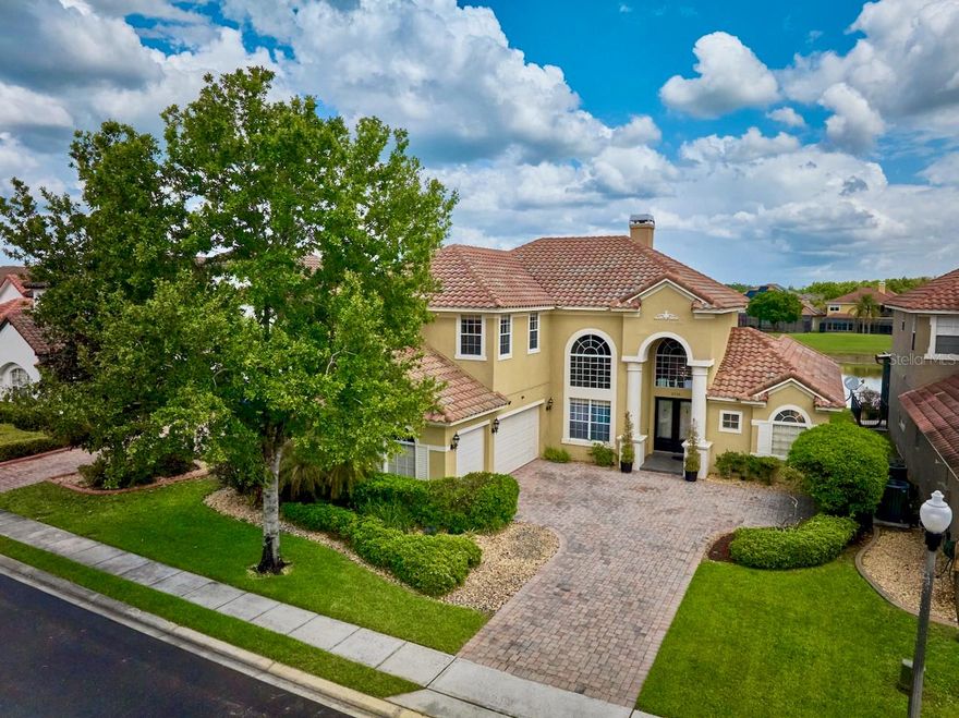 Presenting a rare opportunity to acquire a truly unparalleled, custom-caliber estate that serves as a fully integrated smart home, currently the only offering of its kind available in the area. Spanning over 4,000 square feet, this exceptional 5-bedroom, 4-bathroom residence welcomes you with elegant travertine flooring that leads into an expansive open-concept living space enhanced by textured brick accent walls and modern crystal lighting. Magnificent floor-to-ceiling windows, treated with impact-resistant 3M tinted film and smart blackout shades, perfectly frame unobstructed water and championship golf course views. The chef-inspired kitchen is appointed with expansive granite countertops, updated soft-close cabinetry with pull-out organizers, smart appliances, a premium French door double oven, a Kraus dual-head faucet, and smart accent lighting. This space flows seamlessly into a living area anchored by a wood-burning fireplace featuring glass doors and smart lighting. The highly functional layout includes a versatile main-floor bedroom, a dedicated laundry room equipped with a soaker sink and Maytag appliances, and an oversized 3-car garage featuring insulated doors and a ventilated exhaust AC. Technological upgrades include a Google and ADT integrated security system, three energy-efficient AC units with whole-home UV-C air purifiers, and an in-wall Klipsch whole-home speaker system. The outdoor living experience is extraordinary, featuring an American Paradise outdoor kitchen with a gazebo, exhaust fan, accent lighting, and integrated Klipsch speakers, all designed for al fresco dining. Located in a premier guard-gated resort community known for its championship golf and luxury facilities, this home offers incredible proximity to world-class theme parks, dining, and shopping in the highly sought-after Disney Corridor.