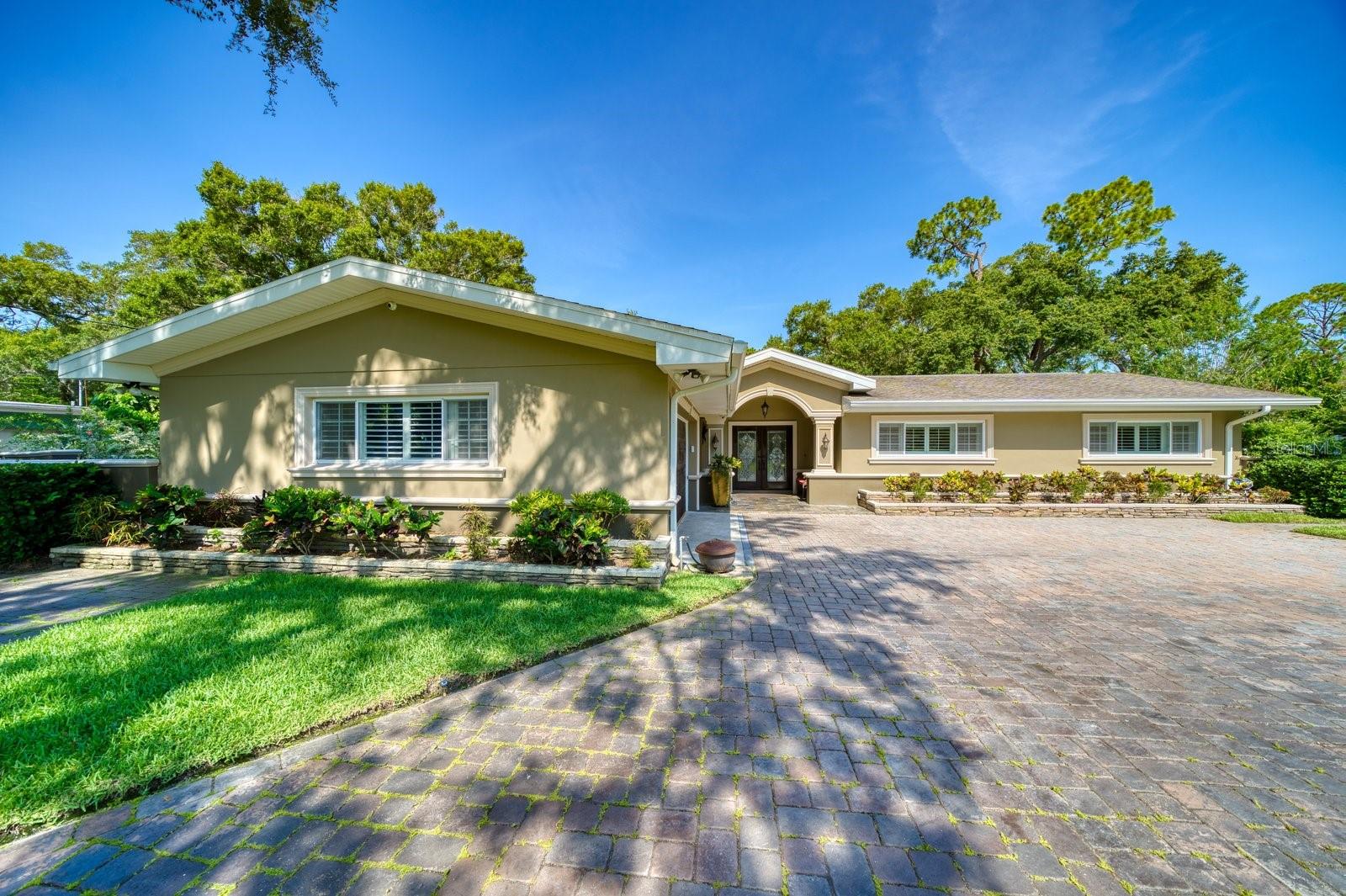 This magnificent Sherwood Manor home is well appointed with 4 bedrooms, 3.5 baths and an oversized 2 car garage. As you step through the double lead-glass doors, the spacious and inviting floor plan beckons you to explore the outdoor paradise beyond. The custom chef's kitchen is a culinary masterpiece, boasting double ovens, a generous island with a wine fridge, dual sink areas, luxurious granite countertops, and sleek soft-close cabinets, making cooking and entertaining an absolute delight. The cozy family room is a sanctuary of comfort, adorned with a recessed ceiling, a captivating wood-burning fireplace, built-in cabinets, and a state-of-the-art BOSE surround sound system. Retreating to the self-contained primary suite is an indulgent experience, with tray ceilings, french doors leading to the serene courtyard, and a dedicated 2 Ton AC and electric panel await. The primary bath epitomizes luxury, featuring a freestanding soaker tub, a separate shower, and an artfully crafted double vanity. The guest rooms are equally spacious and filled with natural light, with the main guest room offering the added convenience of an en-suite bathroom with a shower. The home boasts a total of 7.5 Tons across its three AC systems, ensuring a consistently cool and comfortable environment. The expansive outdoor courtyard is a haven of tranquility and seclusion, a charming Gazebo complete with a bar, water supply, and electricity. With over 3/4 acre of open space, this property is an entertainer's paradise and a true escape into nature's embrace. There is a detached office/guest house offering a well-appointed kitchenette, and powder bath. Centrally located to award-winning white sand beaches, including the nearby Dunedin with its breathtaking Honeymoon and Caladesi islands. Explore the vibrant downtown areas of St. Pete and Tampa International, each just a short drive away. Discover the unparalleled charm and beauty of this truly one-of-a-kind gem, designed for those who appreciate the extraordinary.