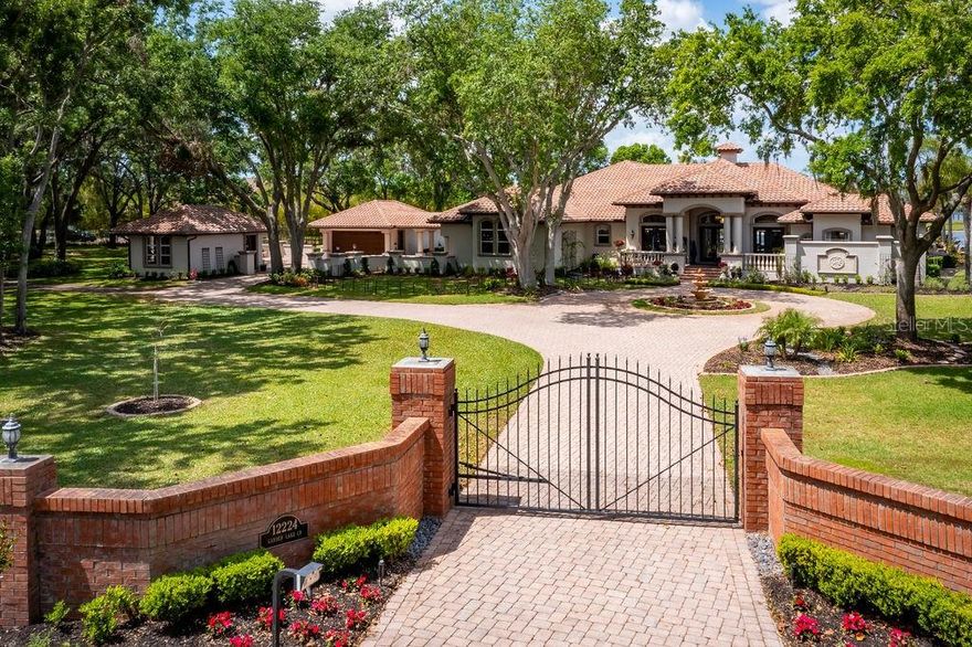 This magnificent 5,304-square-foot, one-story residence offers a resort lifestyle in a prime lakeside location. On three acres, with 180 feet of skiable Lake Breckenridge shoreline, the property boasts privacy and breathtaking views. Upon entering the gated entrance, you're greeted by a spacious brick-paved circular driveway. Inside, the home impresses with its elegant details including crown molding, coffered ceilings with wood inlays and 12-14-foot ceilings. The formal living areas feature custom wall niches, full surround sound and stunning lake views. The chef’s dream kitchen comes equipped with beautiful cabinetry, an oversized island, granite countertops, two dishwashers, a double-oven Wolf gas range, a Decor built-in wall oven and a butler's pantry. The spacious family room is warm and inviting with a stone fireplace, attractive wall niches and 10-foot sliders that offer stunning views and plentiful light. Placed next to the family room is the deluxe media/billiards room, complete with immersive surround sound and a stunning wet bar. The handsome wood bar features a beverage refrigerator and ice maker for easy entertaining. Equally well-appointed is the home office, which focuses on creating a haven for productivity with a custom-built, wood-paneled desk and shelves. The primary bedroom suite is a spacious refuge. Its large closet combines style and elegance with bespoke built-ins, lighted shelving, thoughtfully designed shoe and accessory racks, and quality finishes. The en-suite bath’s generous proportions provide ample space for functionality and aesthetic appeal, creating an oasis of relaxation with its jetted tub, dual vanities and separate commode rooms. The walk-in shower, complete with dual showerheads and massage sprays, offers a spa-like experience. Adjacent to the suite is another bedroom with lake views that’s ideal as a nursery, studio or home gym. Beyond the house, the property boasts an expansive lanai with a resort-style pool complete with automatic multi-colored fiber-optic lighting. Gas-powered tiki torches and a lakeside fire pit with comfortable seating combine to create a relaxing ambiance. Together, the outdoor wet bar and top-of-the-line summer kitchen with a Viking grill, warming drawer, cocktail station and refrigerator provide a setting for outdoor entertaining. Designed for the RV enthusiast, a spacious 48-foot storage barn ensures your vehicle is secure and protected and comes equipped with 50-amp electrical service, cable connectivity, water hookups and a pump station. The three garages, two two-car and one single-car that’s air-conditioned, are well outfitted for car enthusiasts and wrap around a spacious motor court. Meticulously designed landscape lighting transforms the property into a luminous oasis at twilight. The 100-square-foot greenhouse comes equipped with water and electric, and provides essential elements for cultivating a diverse array of plants year-round. If you need a guest house or in-law suite, this beautiful three-acre wooded setting provides ample space for a charming, lakeside casita. Additional features include a whole-house generator with a 1,000-gallon propane tank that can keep the house running for two weeks. This unique combination of luxurious amenities, stunning lake views and copious outdoor entertaining spaces makes this estate an ideal retreat for discerning buyers.