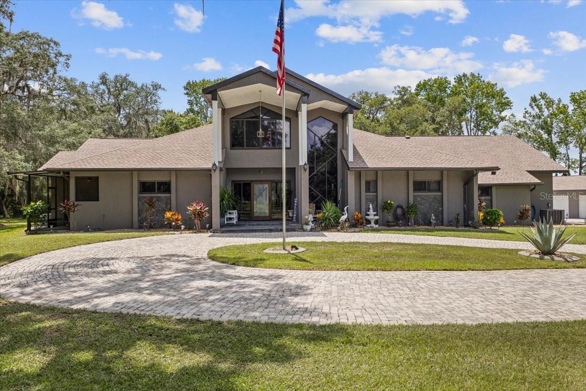 Unique Opportunity! Welcome to your private retreat nestled on 3.34 breathtaking acres in the sought-after Gospel Island area of Inverness. Tucked beneath majestic oaks and set along a serene canal that leads directly to the Tsala-Apopka Chain of Lakes, this one-of-a-kind property is the perfect blend of peace, privacy, and recreation. Whether you're bringing kayaks, a fishing boat, or even an airboat, there's room for it all—thanks to an attached 3-car garage and an impressive 4-bay detached garage with space for up to eight more vehicles or toys. With nearly 4,500 square feet of living space and almost 7,000 square feet under roof, this home was built for comfort and entertaining. Step into a grand foyer that opens to a stunning living room with soaring 22-foot ceilings and a floor-to-ceiling stone fireplace. This spacious 4-bedroom, 5-bathroom home offers flexible living arrangements with private bathroom access for most bedrooms—creating ideal suite opportunities throughout. The master suite is a sanctuary of its own, featuring a cozy gas fireplace, oversized closet, and a luxurious stone-accented en-suite bathroom with a garden tub, walk-in shower, and dual vanities. Thoughtful upgrades include a brand-new roof in 2023, new flooring throughout, and multiple remodeled bathrooms. Fresh paint, new tile, upgraded electric in the garage, new water heaters, and much more, make this purchase an easy YES! Step outside to your own resort-style oasis, where a gorgeous swimming pool, spa with waterfall feature, and a fully equipped outdoor kitchen—including a grill, pizza oven, and ceiling-mounted retractable TV—await. There’s even a dedicated pool bath outside! With two indoor gas fireplaces, tranquil views, and nature all around, this home feels worlds away, yet it's just minutes from downtown Inverness and roughly 15 miles to the Turnpike for easy commuting. Best of all, this peaceful waterfront retreat is priced under appraised value—making it an incredible opportunity for those seeking luxury, land, and a little slice of Florida paradise.